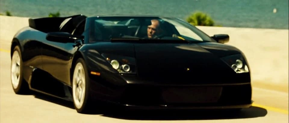 Jason Statham driving black Lamborghini Murcielago Roadster on road