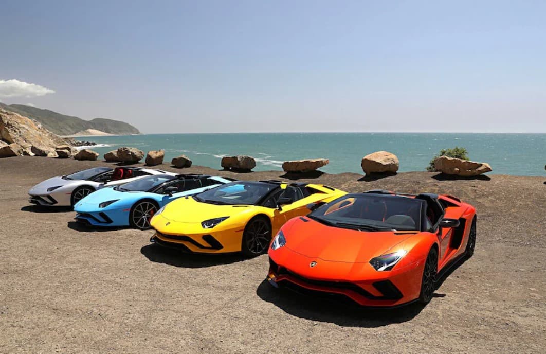Various lamborghinis parked next to the ocean