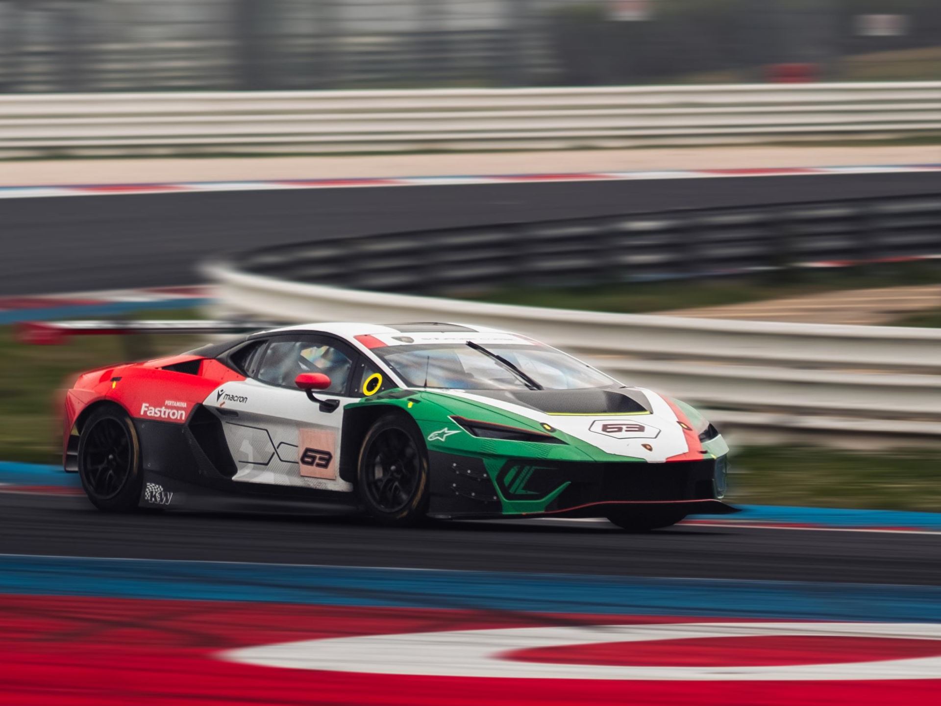 Lamborghini'S First In-House Gt3 Car Faces Brutal Sebring Debut 11 A lamborghini huracan gt3 evo race car, number 63, navigates a turn on a race track, captured with motion blur. The car sports a green, white, and red livery, prominently displaying sponsor logos and