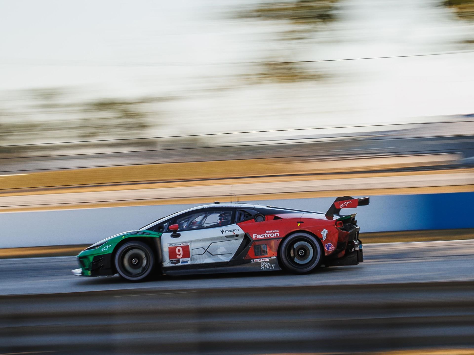Lamborghini'S First In-House Gt3 Car Faces Brutal Sebring Debut 9 A lamborghini huracan gt3 evo race car, number 9, speeds along a race track during the golden hour, with motion blur emphasizing its velocity. The car's green, white, and red livery stands out against