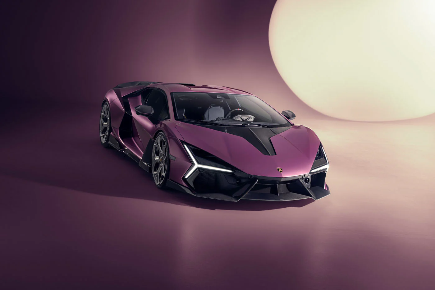 Novitec'S 1,048 Hp Revuelto Program: What It Offers That Lamborghini'S Own Ad Personam Cannot 23 A purple lamborghini revuelto is displayed in a studio with a large circular light in the background, viewed from the front-three-quarter angle. The car's sharp lines and aggressive stance are highlig