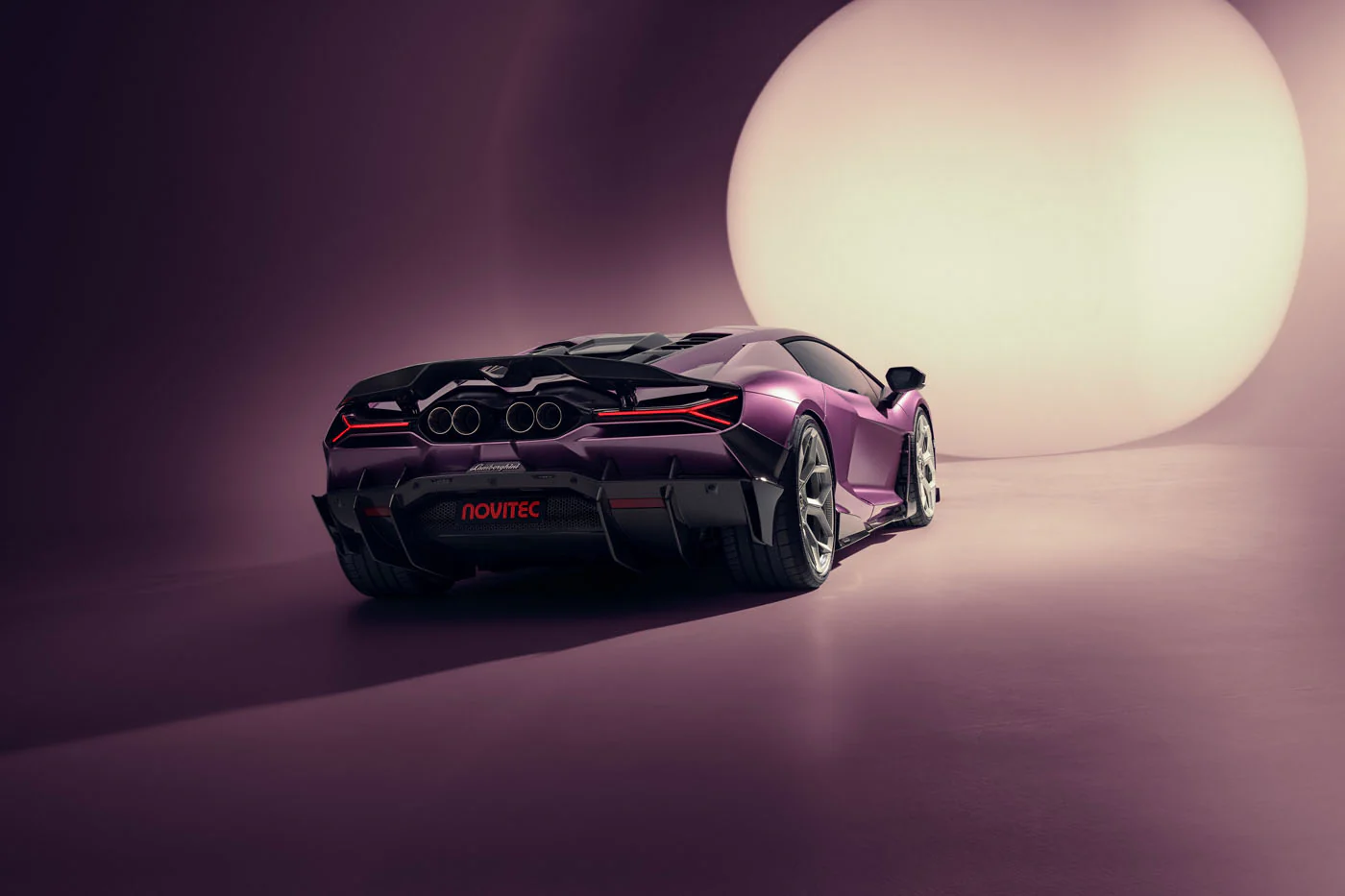 Novitec'S 1,048 Hp Revuelto Program: What It Offers That Lamborghini'S Own Ad Personam Cannot 35 A purple novitec lamborghini revuelto is captured from a low 3/4 rear angle in a studio, with a large circular light illuminating the background. The car's aggressive rear design, including its quad e
