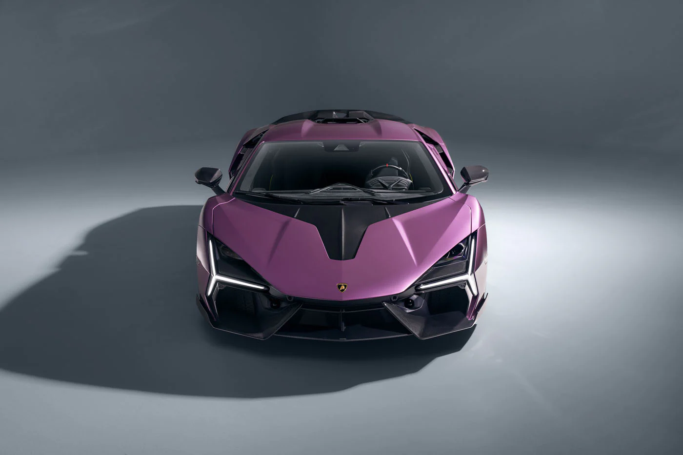 Novitec'S 1,048 Hp Revuelto Program: What It Offers That Lamborghini'S Own Ad Personam Cannot 21 A top-down front view of a purple lamborghini revuelto in a studio, showcasing its symmetrical and aggressive front design. The sharp angles and prominent air intakes are clearly visible, emphasizing