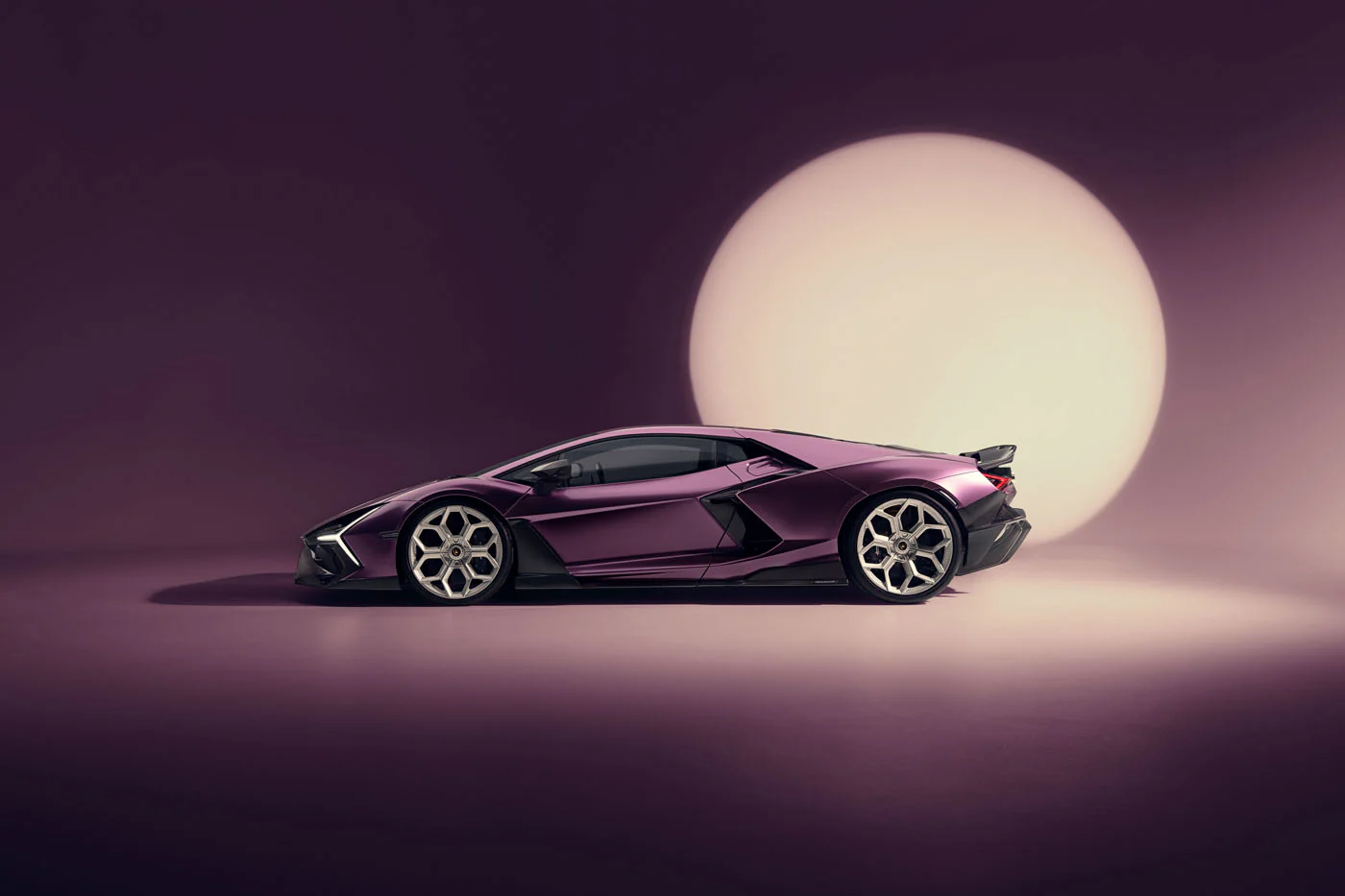 Novitec'S 1,048 Hp Revuelto Program: What It Offers That Lamborghini'S Own Ad Personam Cannot 31 A sleek purple lamborghini revuelto is showcased in a studio setting, illuminated by a large, soft circular light in the background. The car's aggressive lines and custom wheels are highlighted agains
