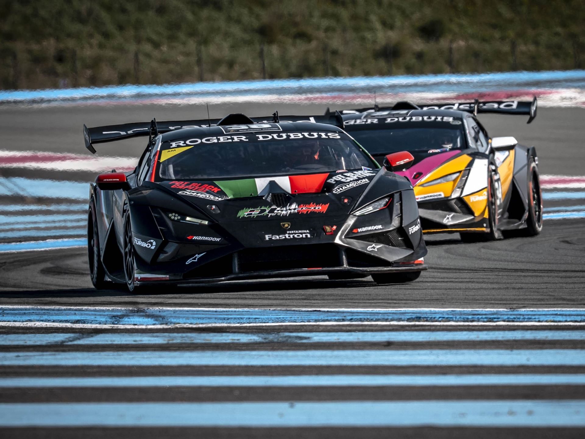 30 Huracán Super Trofeo Evo2S Hit Paul Ricard This Weekend As Lamborghini'S V10 One-Make Series Enters Year 18 3 A black lamborghini huracán race car with italian flag stripes leads another car through a corner at circuit paul ricard