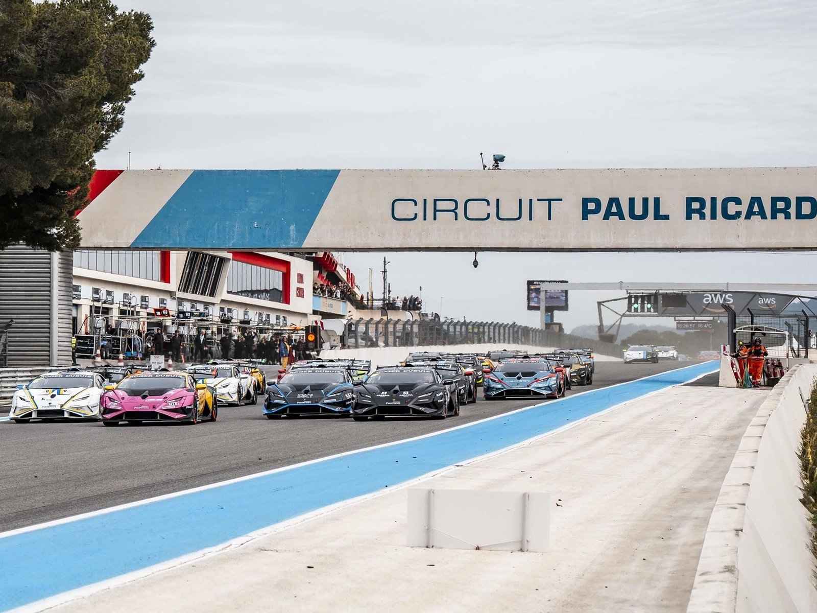 Lamborghini Huracán race cars lined up on the starting grid at Circuit Paul Ricard with colorful liveries and large rear wings visible