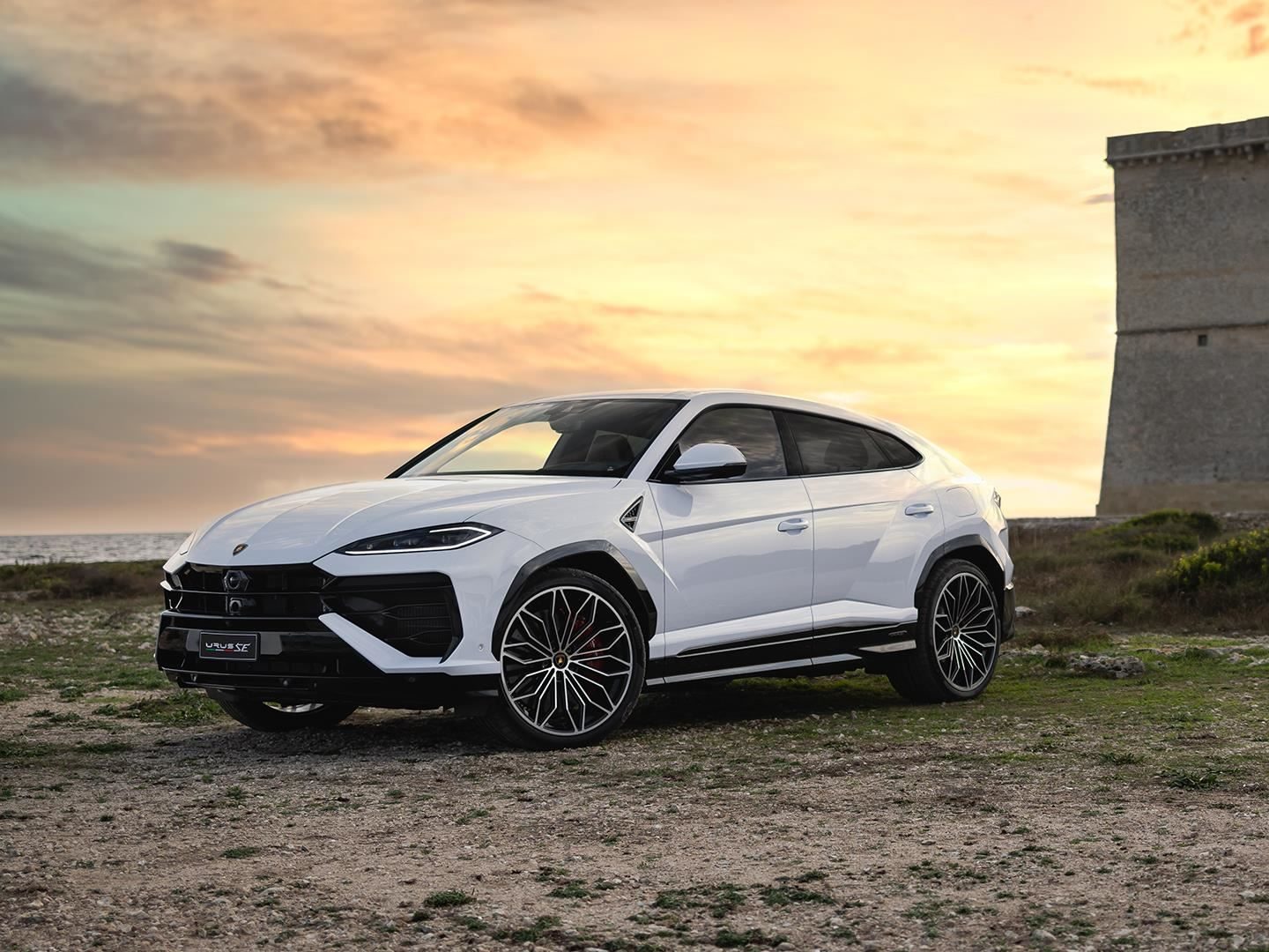 Lamborghini'S April Fool'S Joke Accidentally Reveals The Most Underrated Reason To Buy One 9 White lamborghini urus parked near a coastal stone tower at sunset