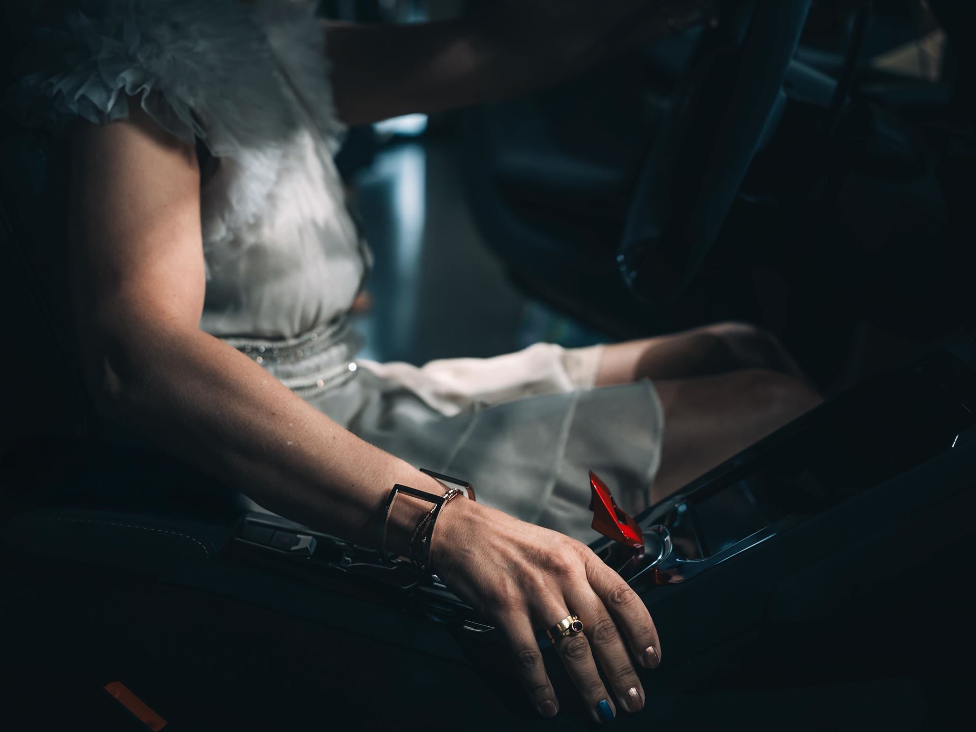 A hand resting on a Lamborghini center console highlighting the red fighter-jet-style start button cover