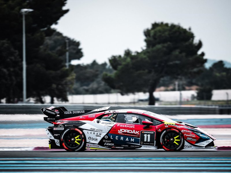 A red, white, and black Lamborghini Huracán Super Trofeo EVO2 race car speeds along Circuit Paul Ricard, its large rear wing and diffuser prominent against a blurred background