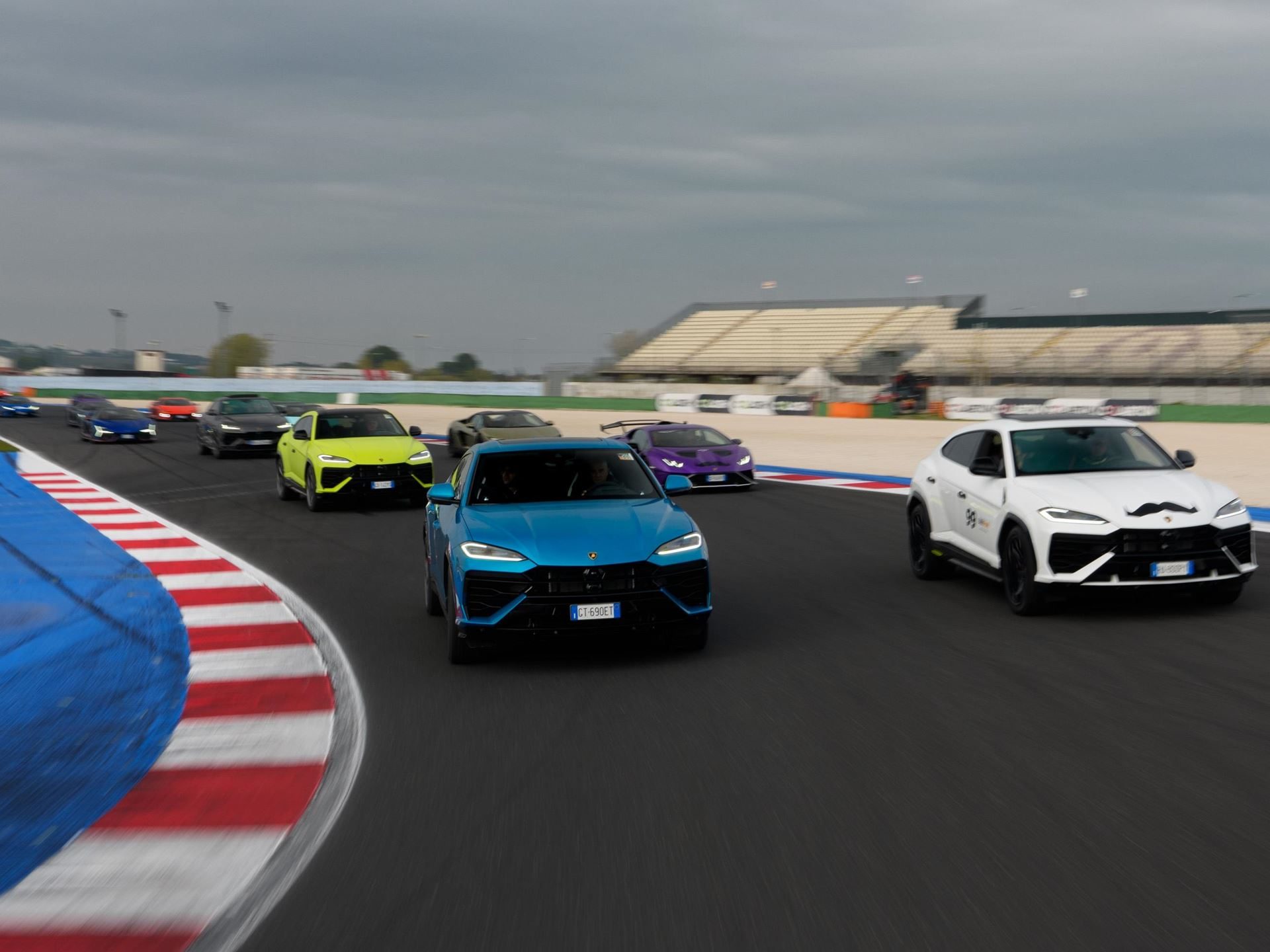 Eleven Winners, Seven Champions: The Huracán Super Trofeo Evo2'S Triumphant Farewell At Misano 7 Convoy of colorful lamborghini urus suvs driving on the misano race track with a blue urus leading