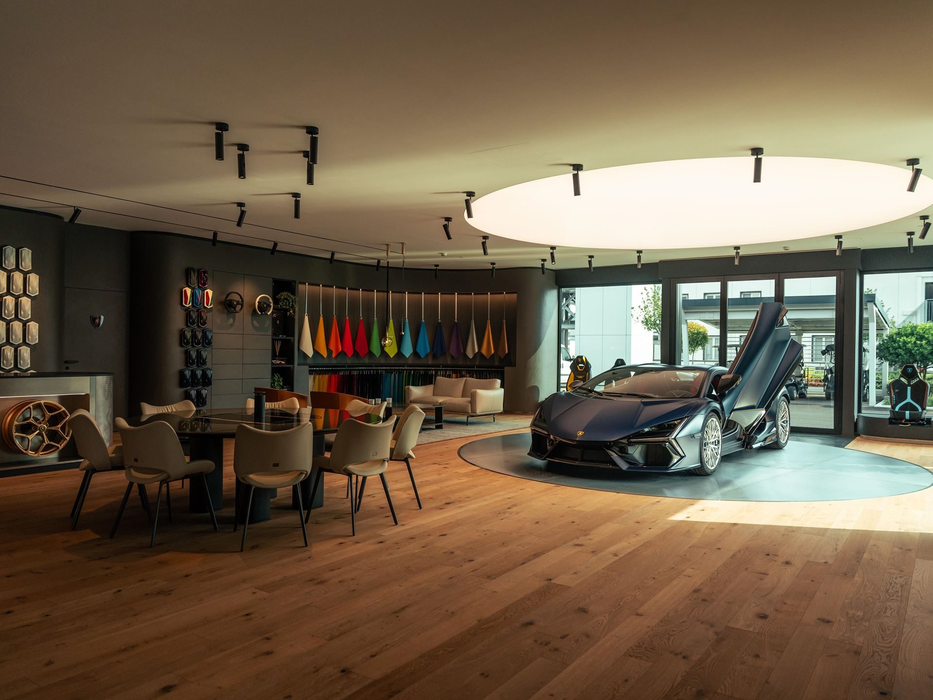 Lamborghini'S Ad Personam Turns 20 With A Miura-Inspired Paint That 96% Of Buyers Should Care About 9 Dark blue lamborghini revuelto with scissor doors open on a circular platform in the ad personam studio, surrounded by customization samples