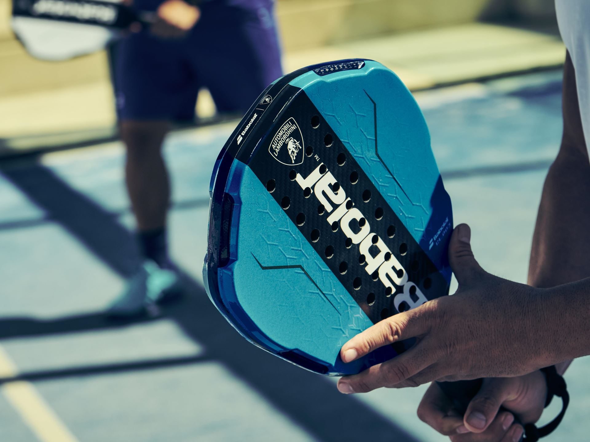 Lamborghini'S Koridion Foam Now Lives Inside A Padel Racquet: The Bl003 Explained 5 Close-up of player holding blue babolat bl003 padel racquet with lamborghini logo during match