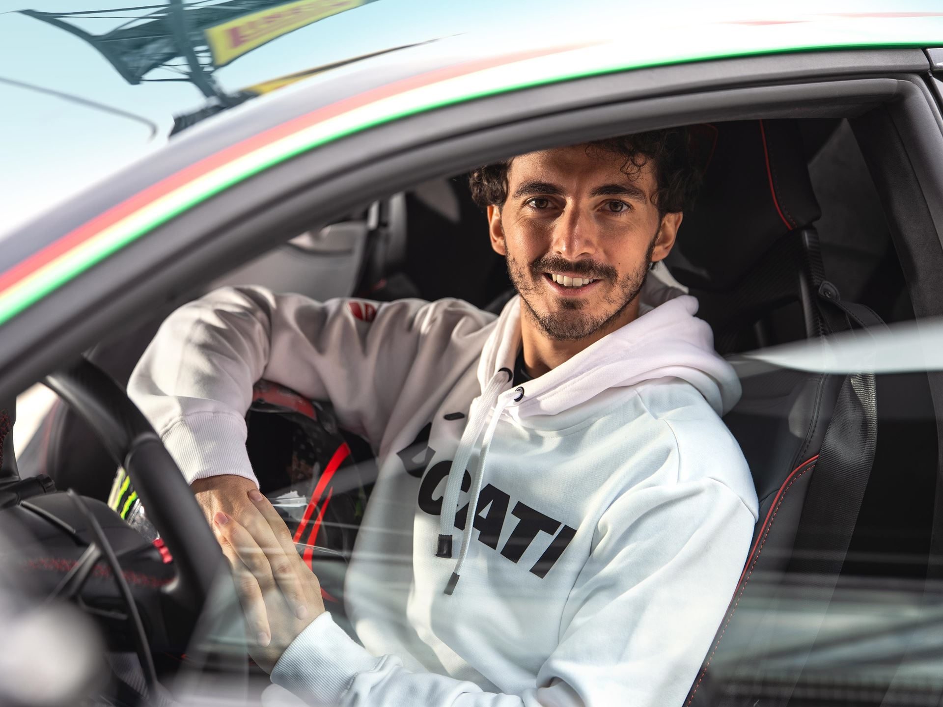 Motogp Champion Pecco Bagnaia Reports The Temerario'S Twin-Turbo V8 Feels Naturally Aspirated At 10,000 Rpm 3 Francesco bagnaia smiling from the driver's seat of the lamborghini temerario, holding his helmet, with italian flag stripe on the door frame and red stitching visible