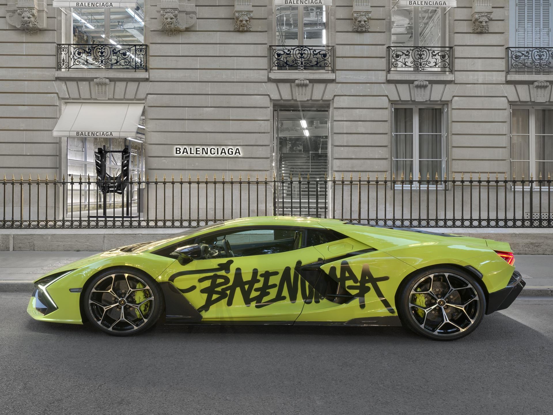 Balenciaga Lamborghini Collaboration Puts Temerario Artwork On The Runway And Graffiti-Wrapped Revueltos Outside Flagships Worldwide 7 Vibrant lime green lamborghini revuelto with balenciaga graffiti-style livery parked outside a classic stone balenciaga store