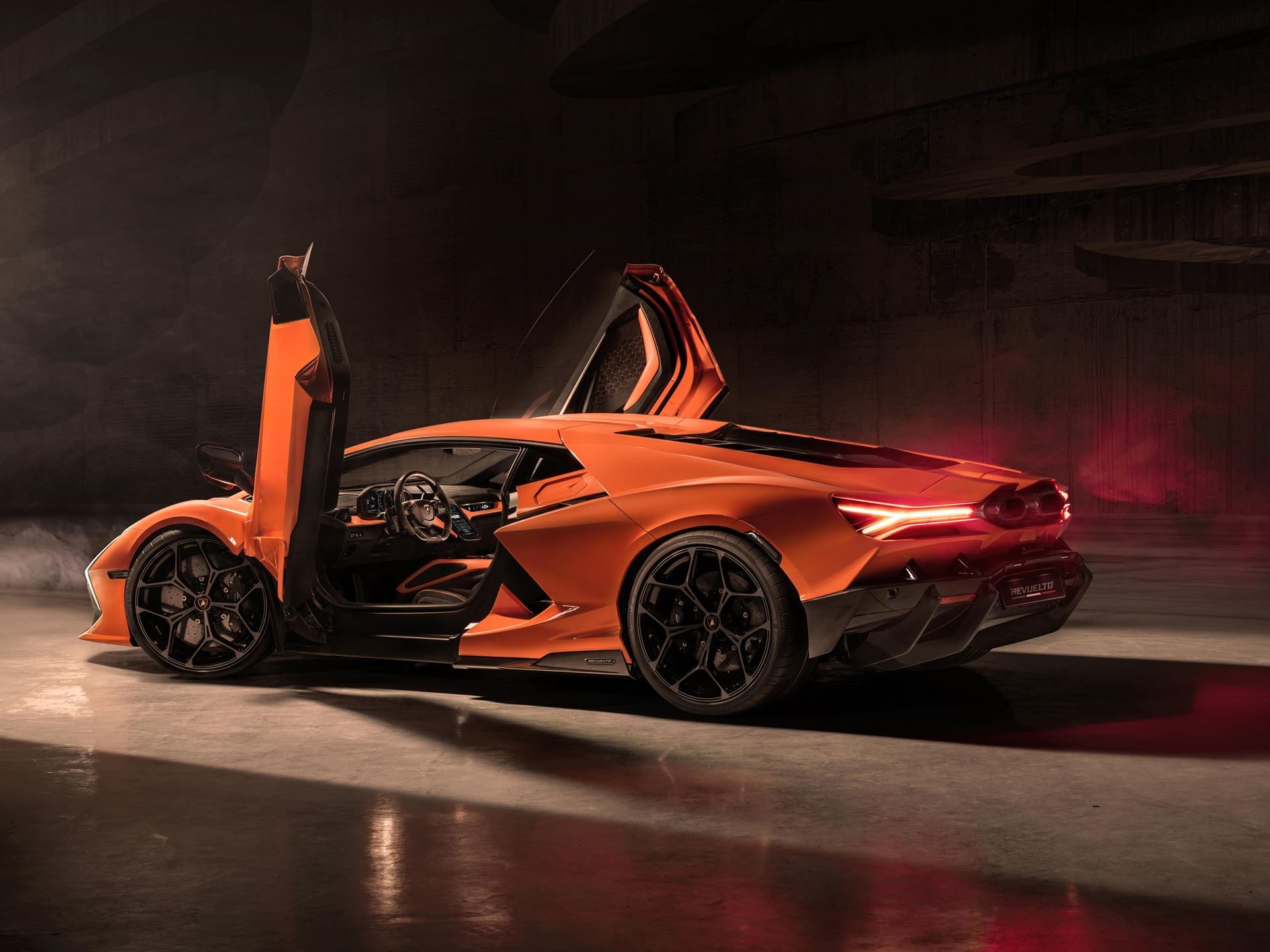 Every Lamborghini In The Lineup Just Won A Red Dot Award, And The Revuelto Took Top Honors 3 Rear three-quarter view of an orange lamborghini revuelto with scissor doors open in a dark studio