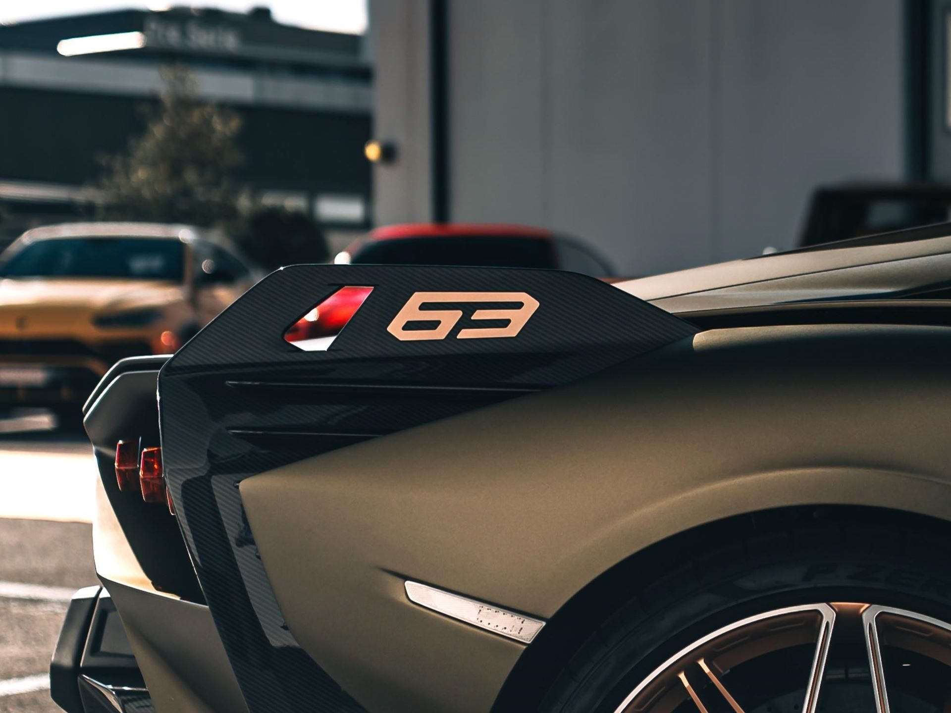 Close-up of the 63 emblem on the carbon fiber rear quarter panel of a matte gold lamborghini sián fkp 37