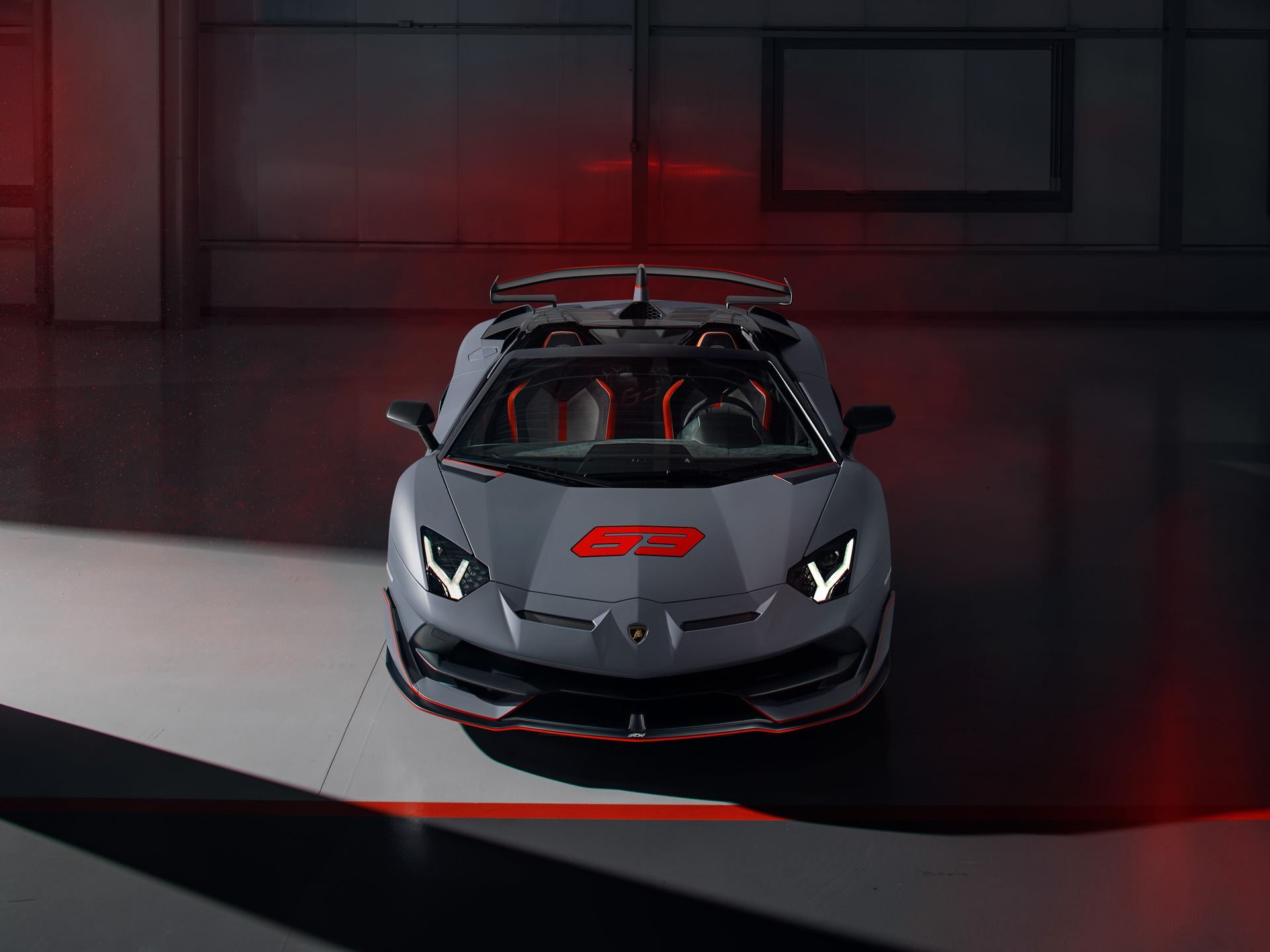 Grey lamborghini aventador svj 63 roadster with red accents and the number 63 on the hood in a studio setting