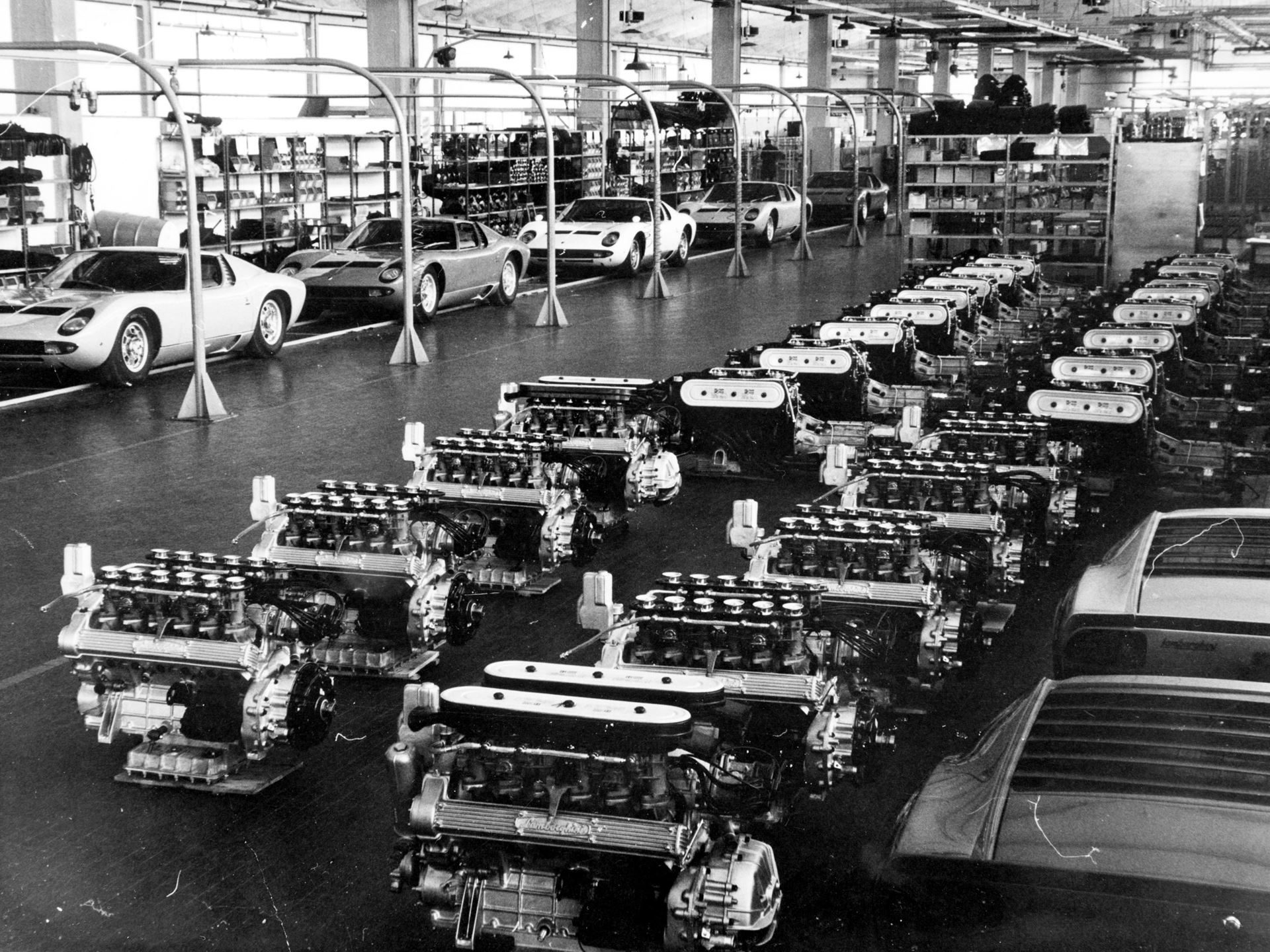 Vintage black and white photograph of the lamborghini factory floor showing miura chassis and v12 engines during assembly