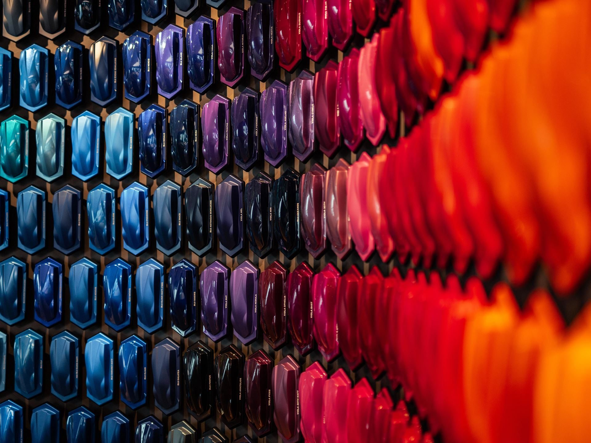 Why Lamborghini Names Its Paint Colors After Greek Gods And Diamond Dust 3 Close-up of a wall displaying numerous hexagonal lamborghini paint samples in a color gradient from blues to oranges