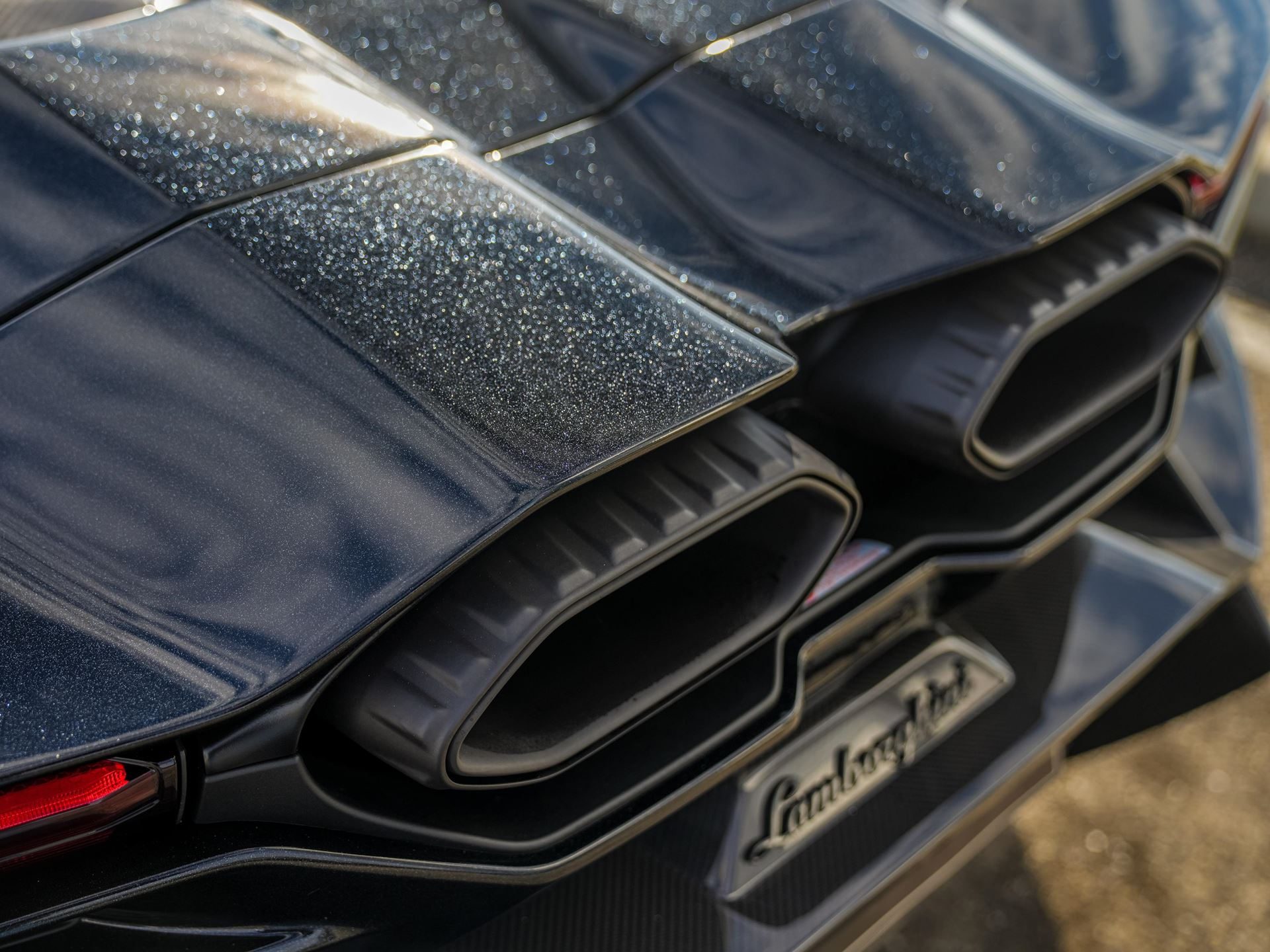 Why Lamborghini Names Its Paint Colors After Greek Gods And Diamond Dust 11 Close-up of the rear exhaust and engine cover of a black lamborghini revuelto showing a subtle glitter effect in the paint