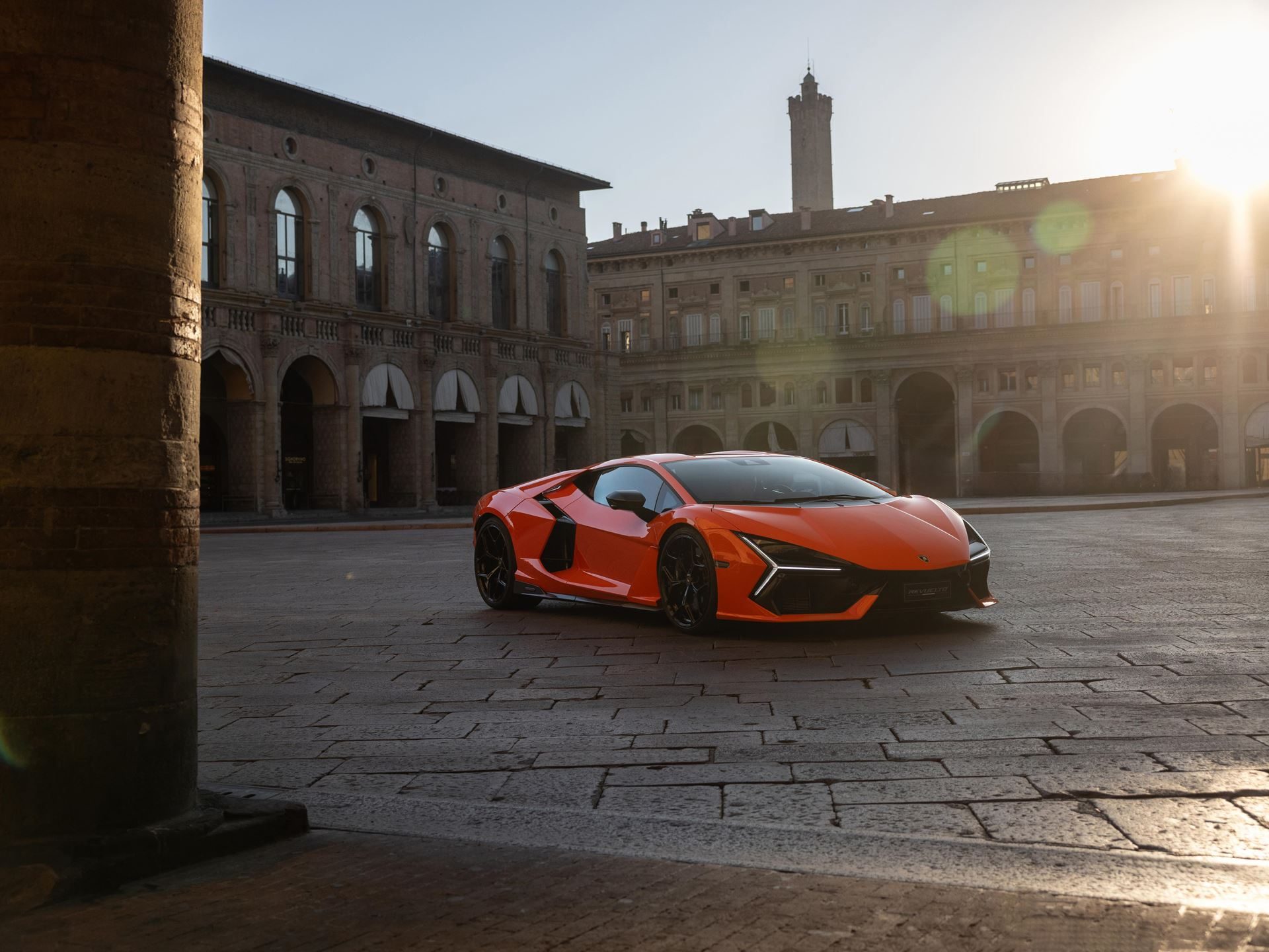 Why Lamborghini Names Its Paint Colors After Greek Gods And Diamond Dust 7 An orange lamborghini revuelto parked in a historic european city square at sunrise