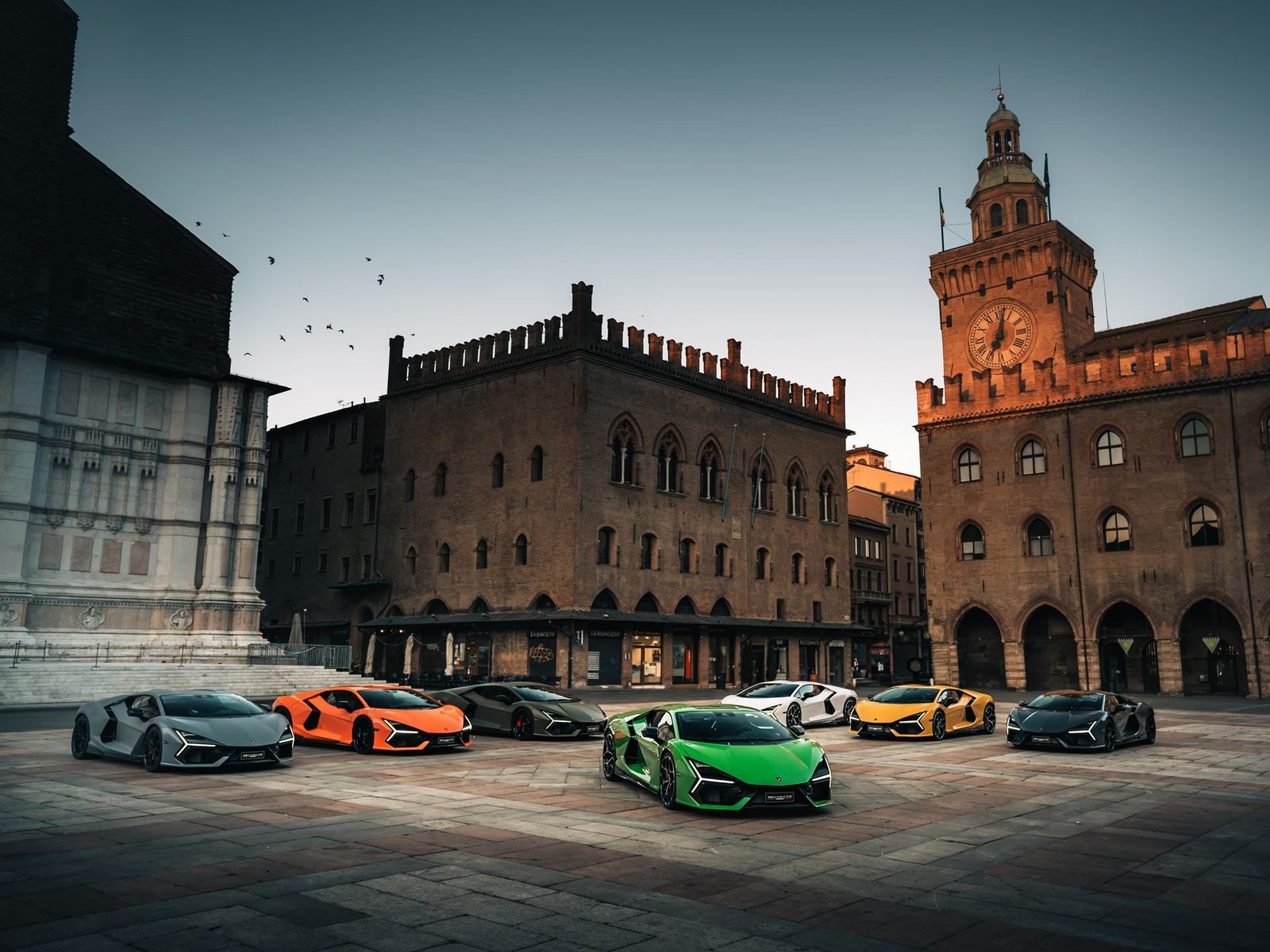 Several Lamborghini Revuelto models in various Ad Personam colors parked in a historic European city square