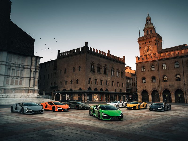 Several Lamborghini Revuelto models in various Ad Personam colors parked in a historic European city square