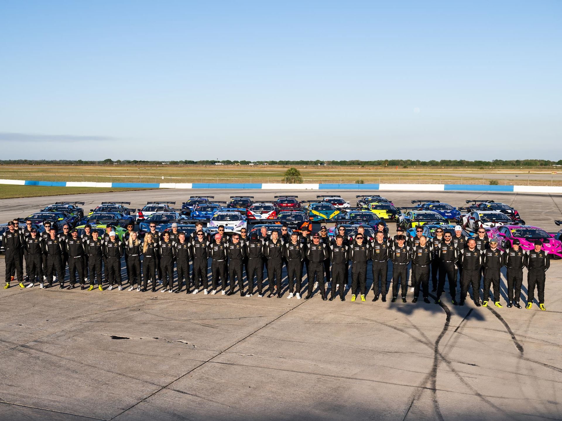 Alpinestars Will Suit Up Lamborghini'S Entire Racing Operation, From Super Trofeo To Lmdh 9 Large group of lamborghini super trofeo drivers in black racing suits standing in front of a fleet of huracán gt3 race cars