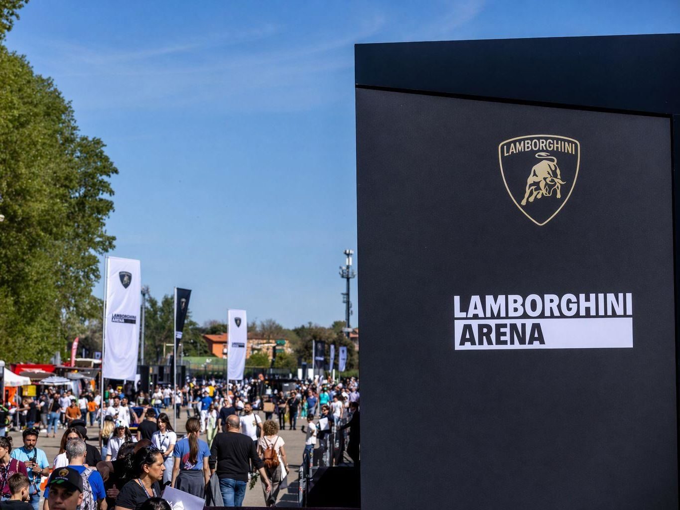 Lamborghini Arena Turns Imola Into A Brand Theme Park, While The Revuelto Sv Lurks Nearby 5 Split image showing a large crowd at the lamborghini arena outdoor event and a close-up of the official lamborghini arena branding sign