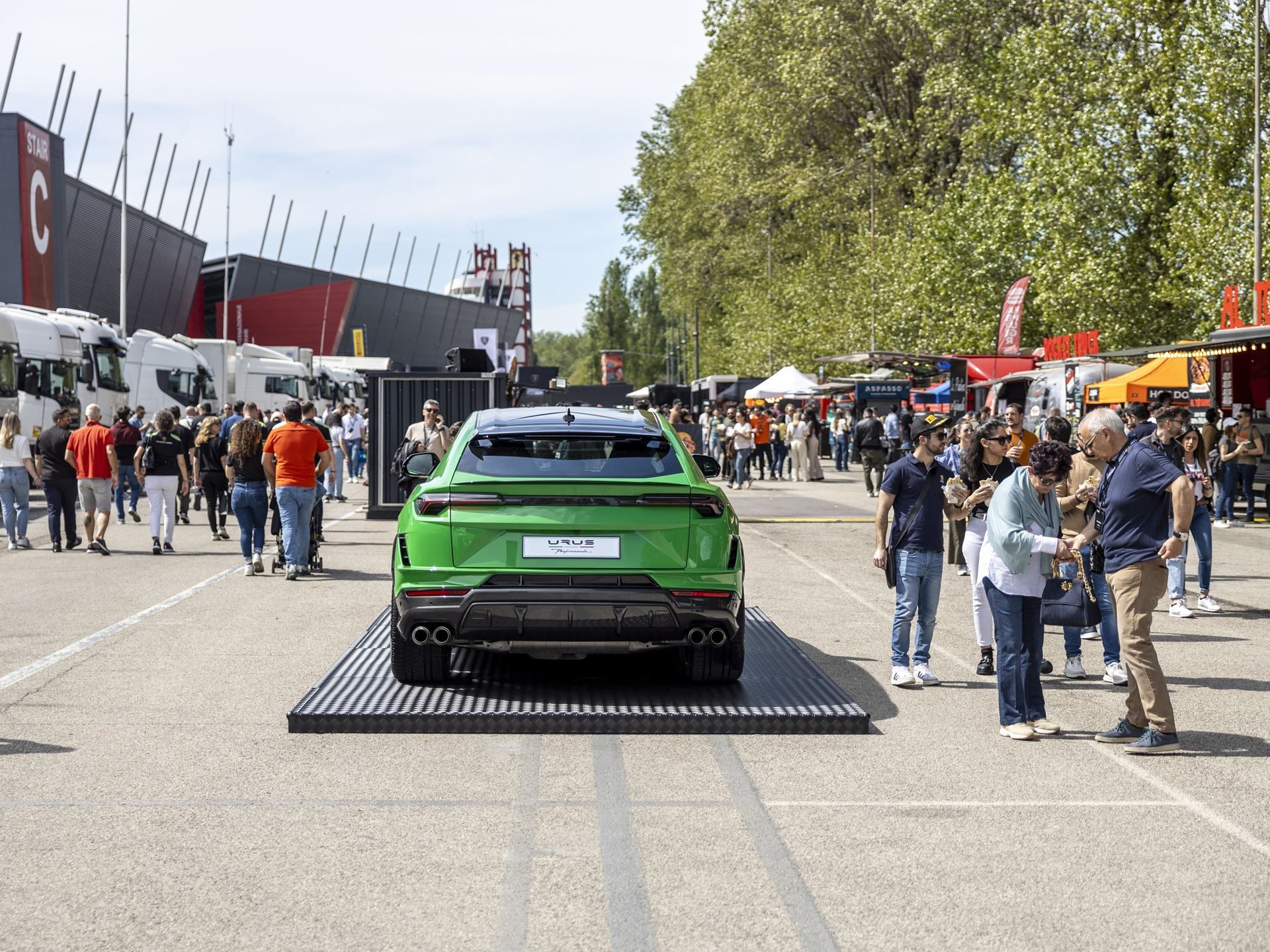 Lamborghini Arena Turns Imola Into A Brand Theme Park, While The Revuelto Sv Lurks Nearby 17 Green lamborghini urus displayed on a platform at the lamborghini arena event with crowds walking past