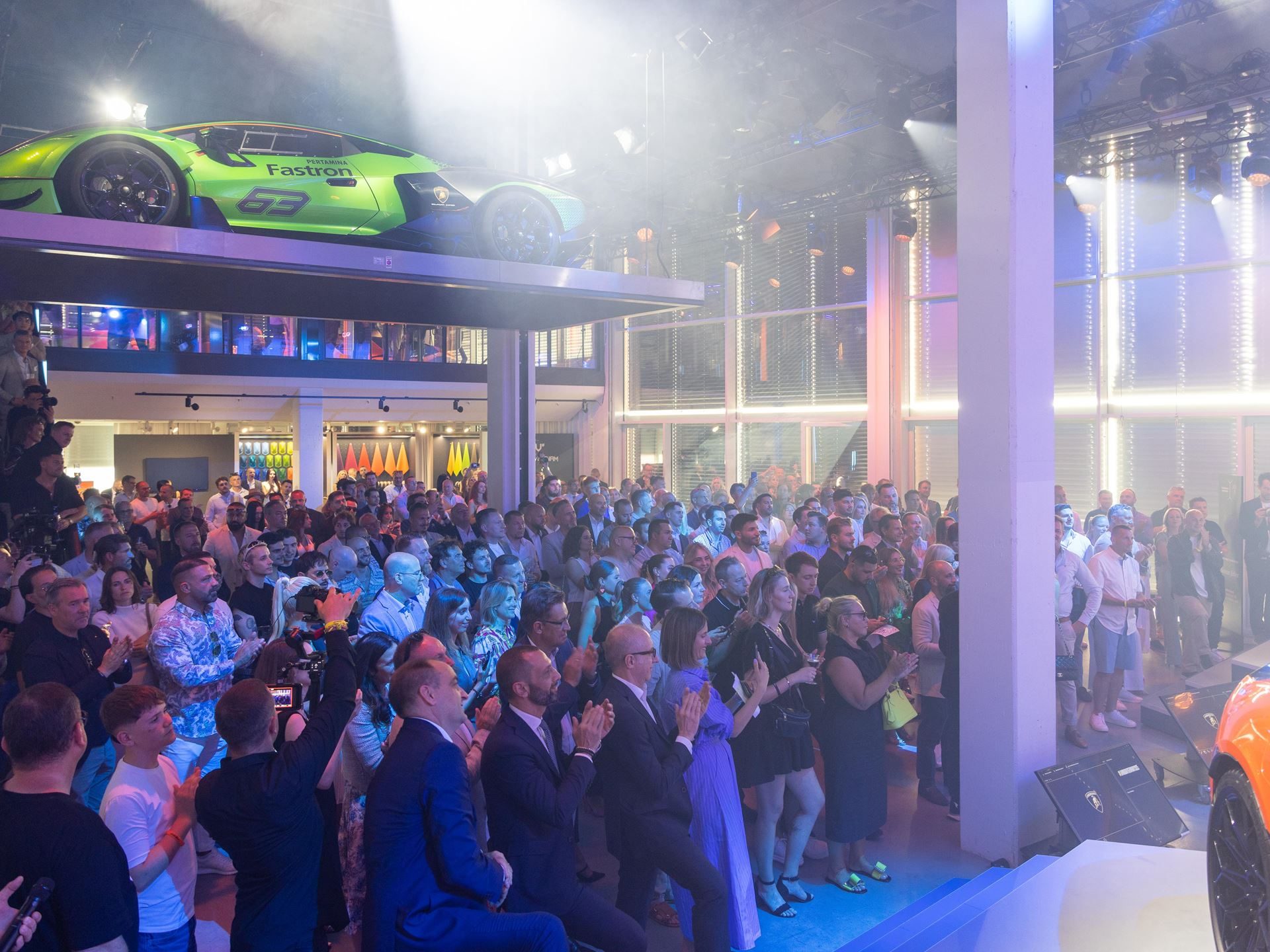 Lamborghini Day Germany 2025 Puts The Fully Electrified Lineup On Display In Munich 5 Large crowd applauding at lamborghini day germany 2025 with a green essenza scv12 on an elevated platform in the background