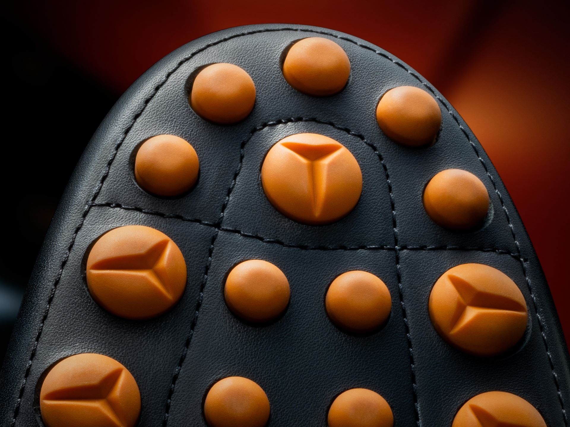 Extreme close-up of the sole of a Tod's for Automobili Lamborghini driving shoe showing orange rubber gommino pebbles with Y-shaped design elements