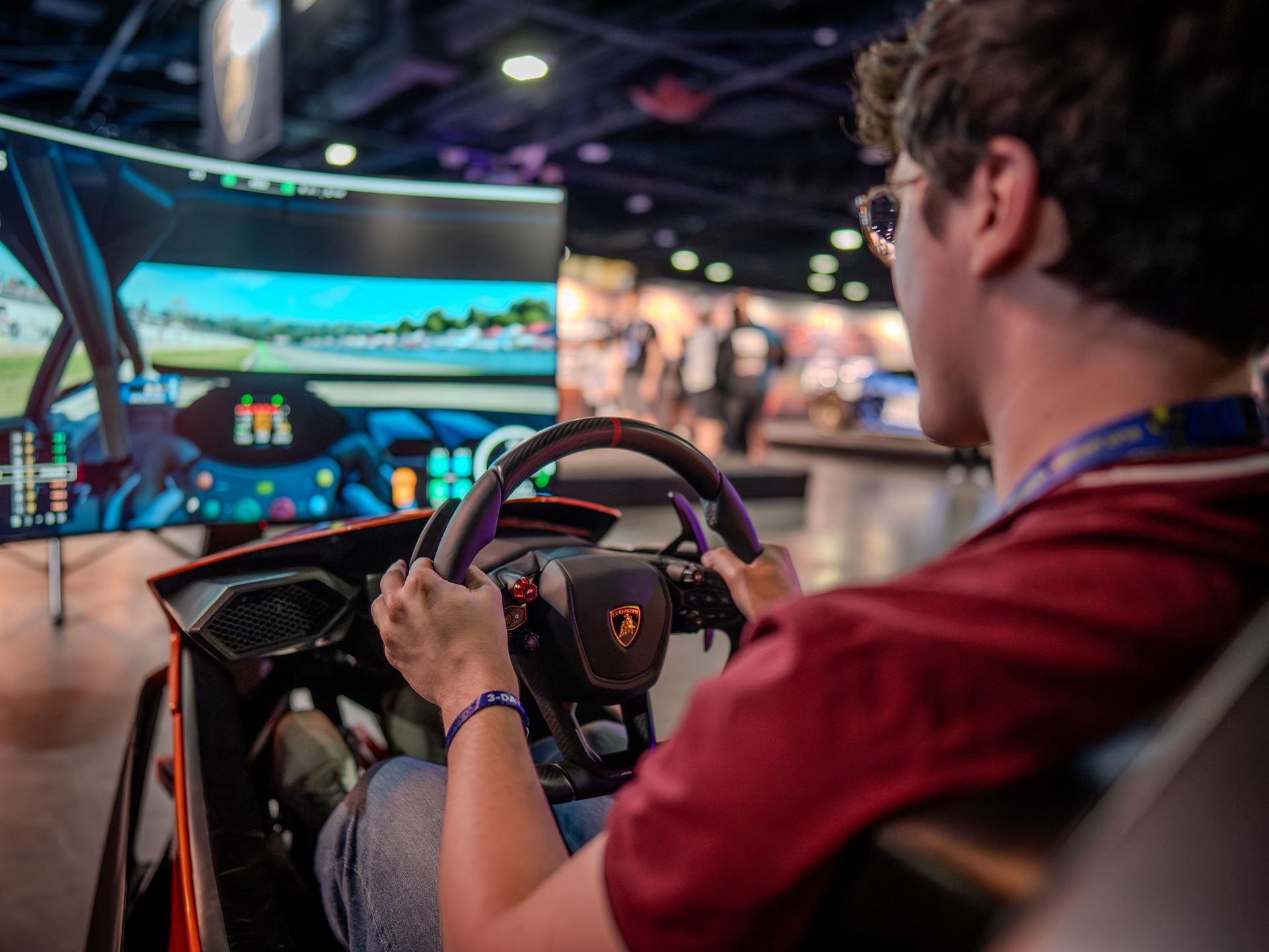 A person playing a racing simulator with a lamborghini-branded steering wheel at dreamhack atlanta 2026