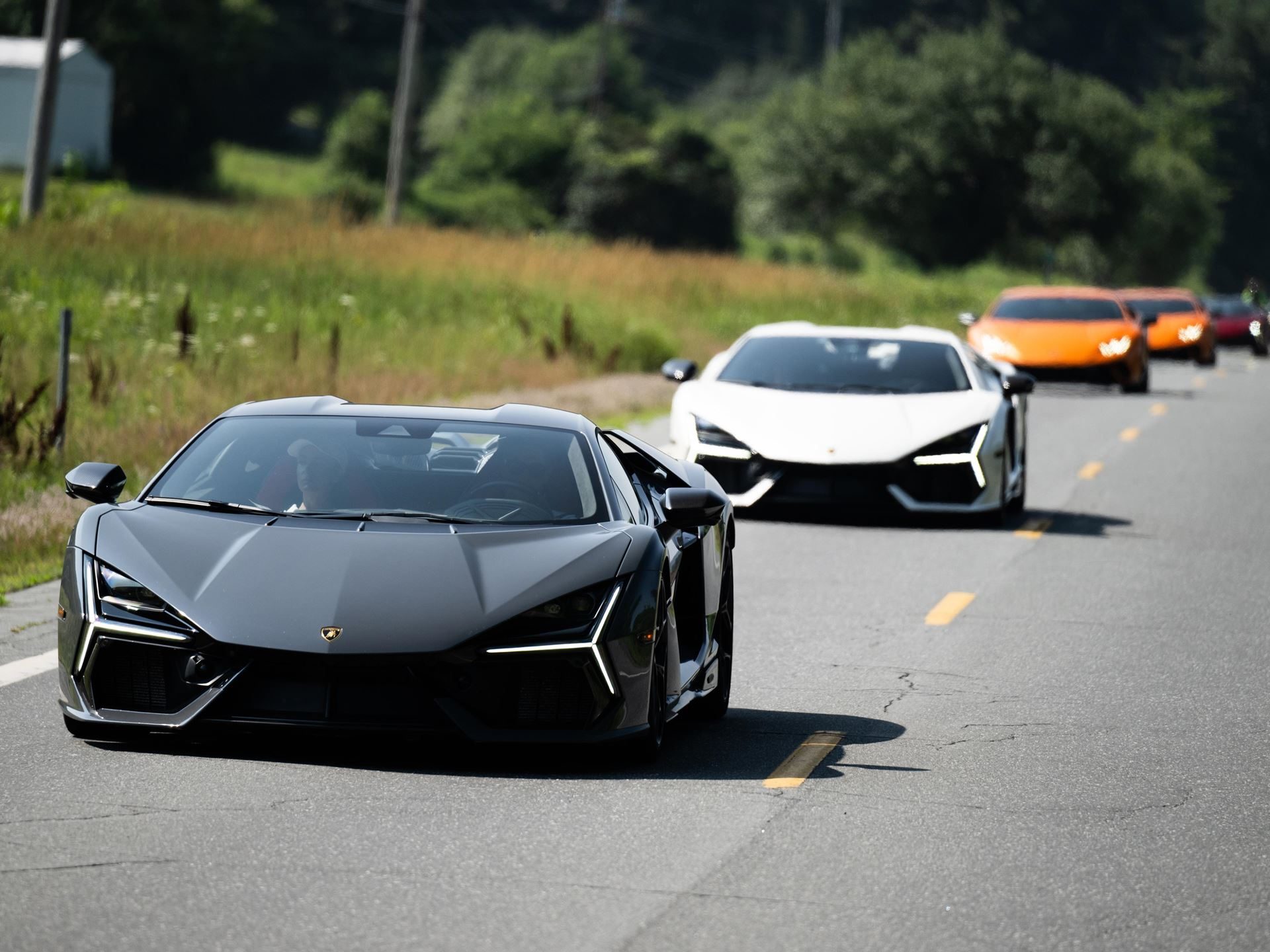 449 Miles Of New England Back Roads With 30 Lamborghinis: Inside The Esperienza Giro Usa 3 A dark grey lamborghini revuelto leads a line of supercars on a sunny new england country road