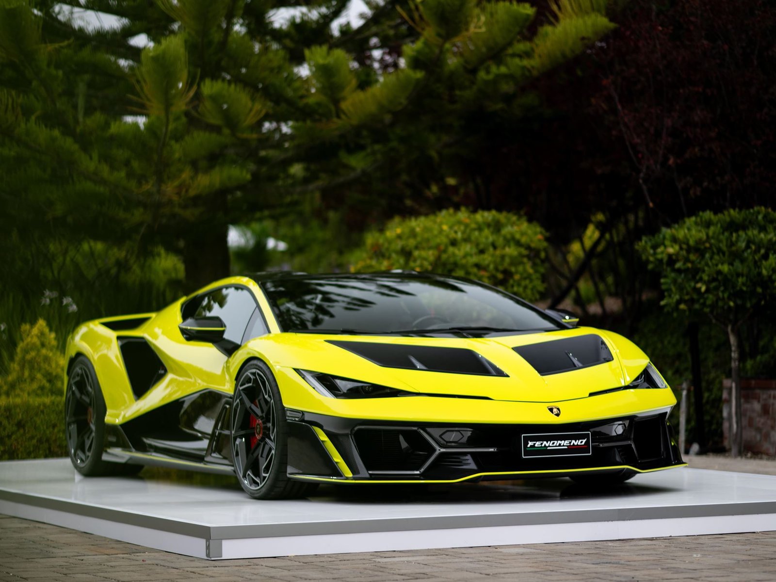 Yellow and black Lamborghini Fenomeno displayed on a white platform at Monterey Car Week 2025