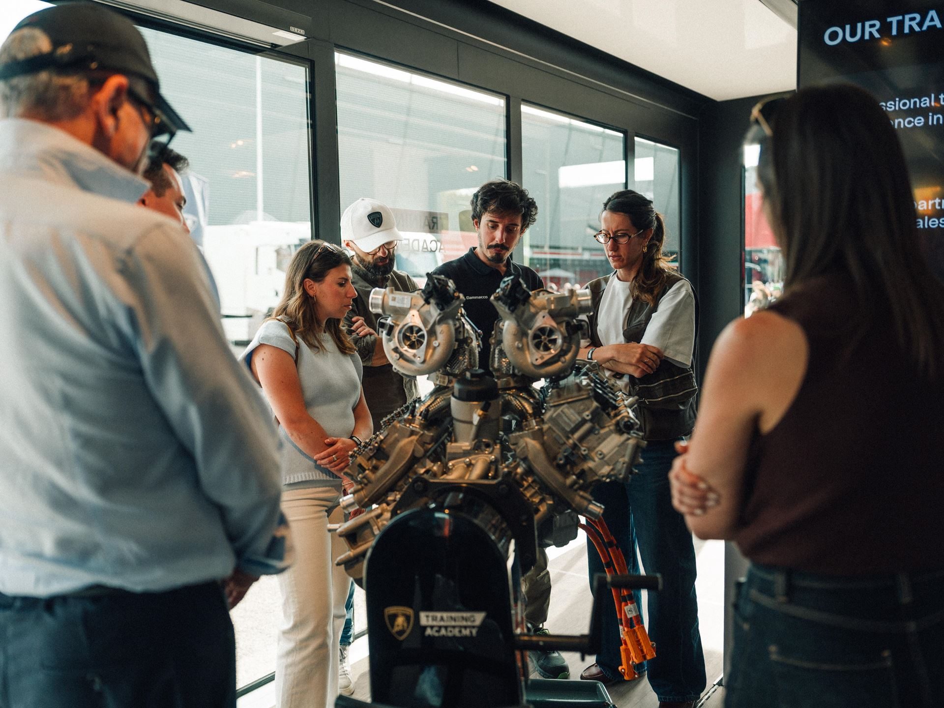 Fenomeno Roadster: 15 Units Of 1,080 Cv Open-Top V12 Fury Headline Lamborghini Arena 2026 5 Attendees gathered around a detailed lamborghini engine display at the training academy exhibit during arena 2026