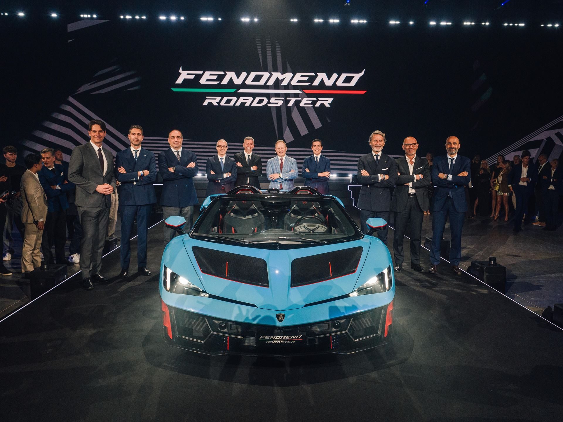 Fenomeno Roadster: 15 Units Of 1,080 Cv Open-Top V12 Fury Headline Lamborghini Arena 2026 3 Lamborghini executives posing with the fenomeno roadster in blu cepheus at its world premiere during arena 2026 party night