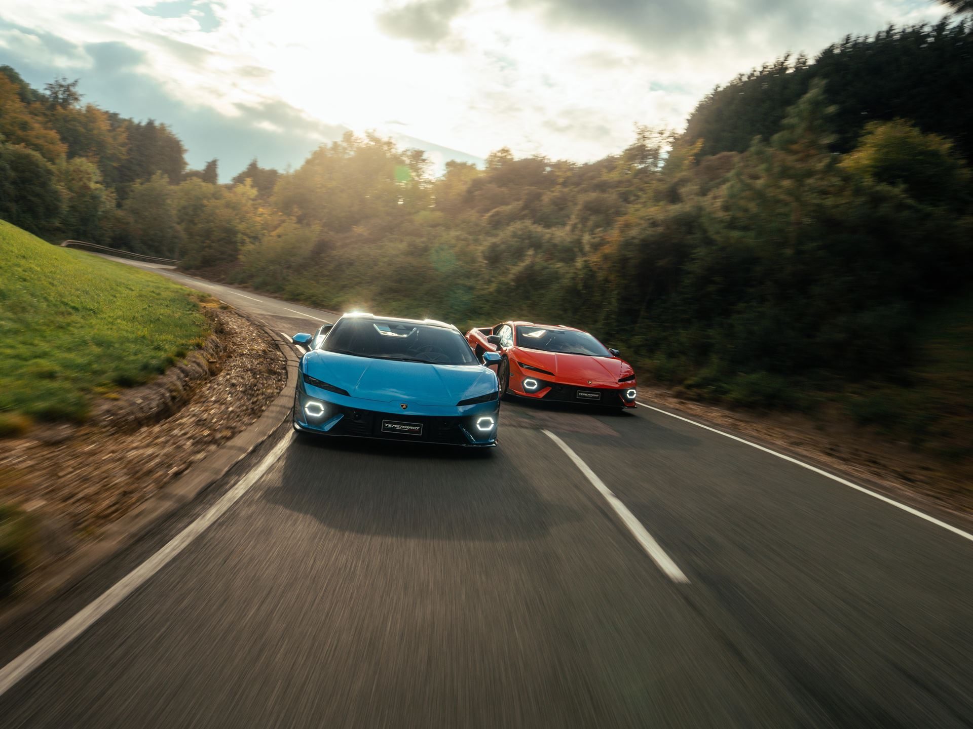 Lamborghini Day Uk Puts The Sold-Out Fenomeno And Drivable Temerario In Front Of 300 Owners At Millbrook 3 Two lamborghini temerario prototypes, one blue and one orange, driving side-by-side on a winding road