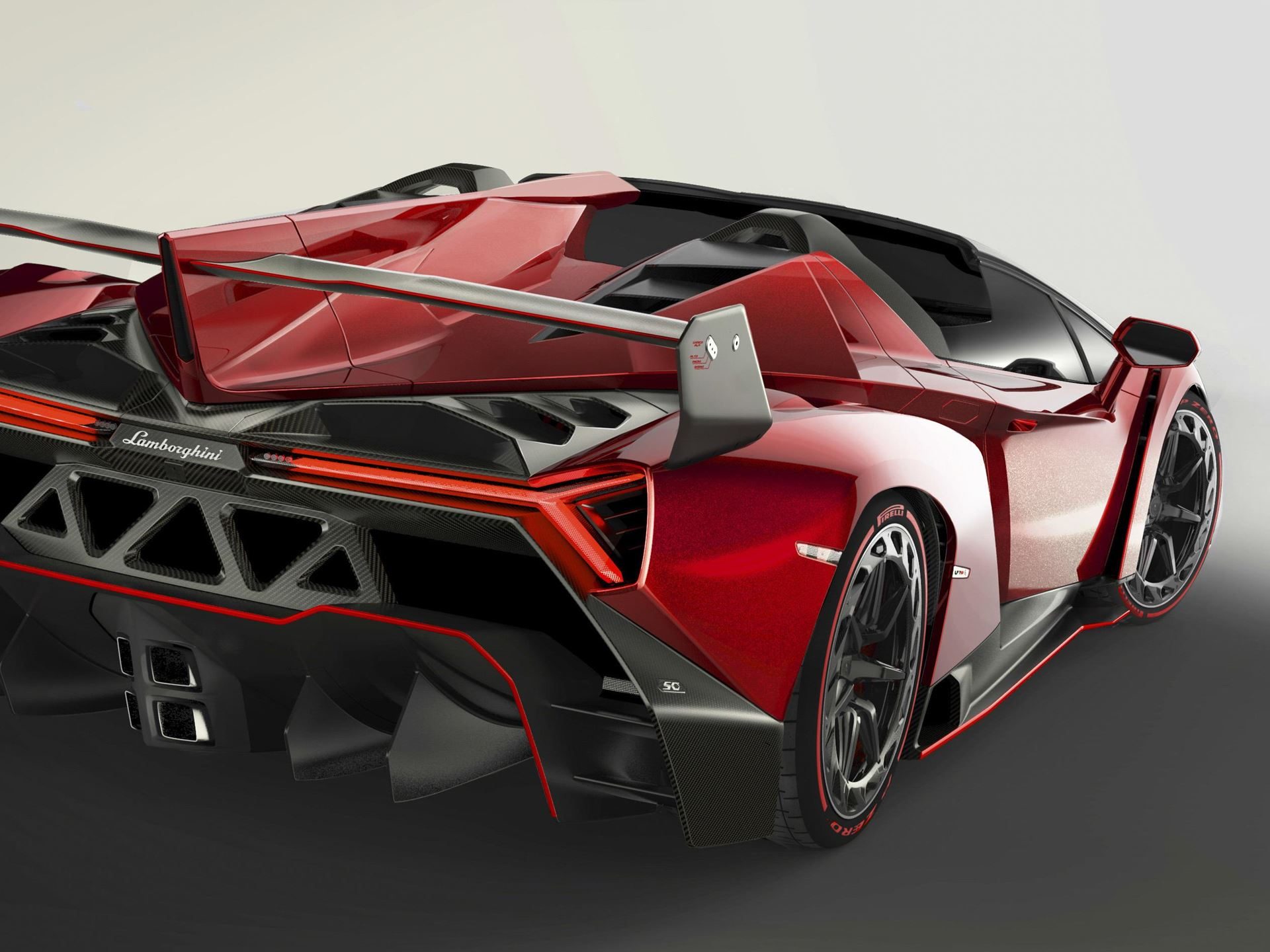 Rear view of the red lamborghini veneno roadster in a studio showing its massive rear wing, intricate diffuser, and y-shaped taillights