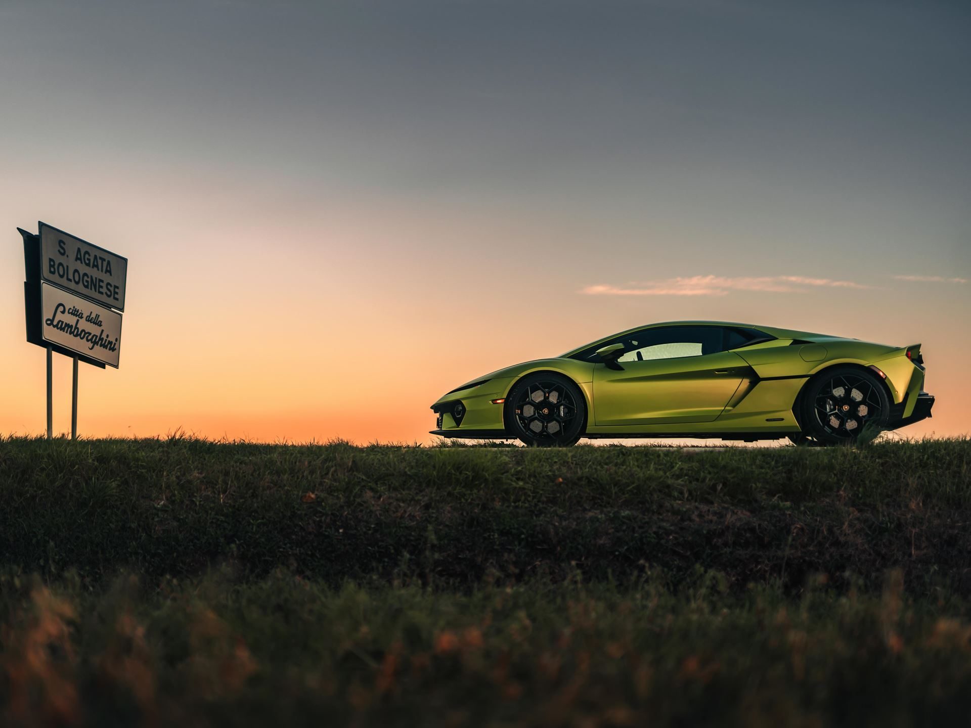 Lamborghini'S First Sustainability Report Reveals A Paradox: Emissions Rose While Every Car Went Hybrid 7 Lime green lamborghini revuelto parked beside the sant'agata bolognese road sign at sunset