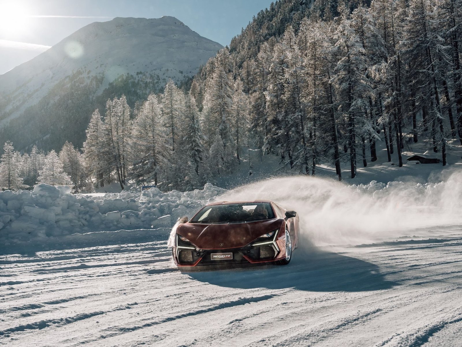 Red Lamborghini Revuelto driving through a snowy mountain landscape, showcasing the hybrid supercar's all-weather capability
