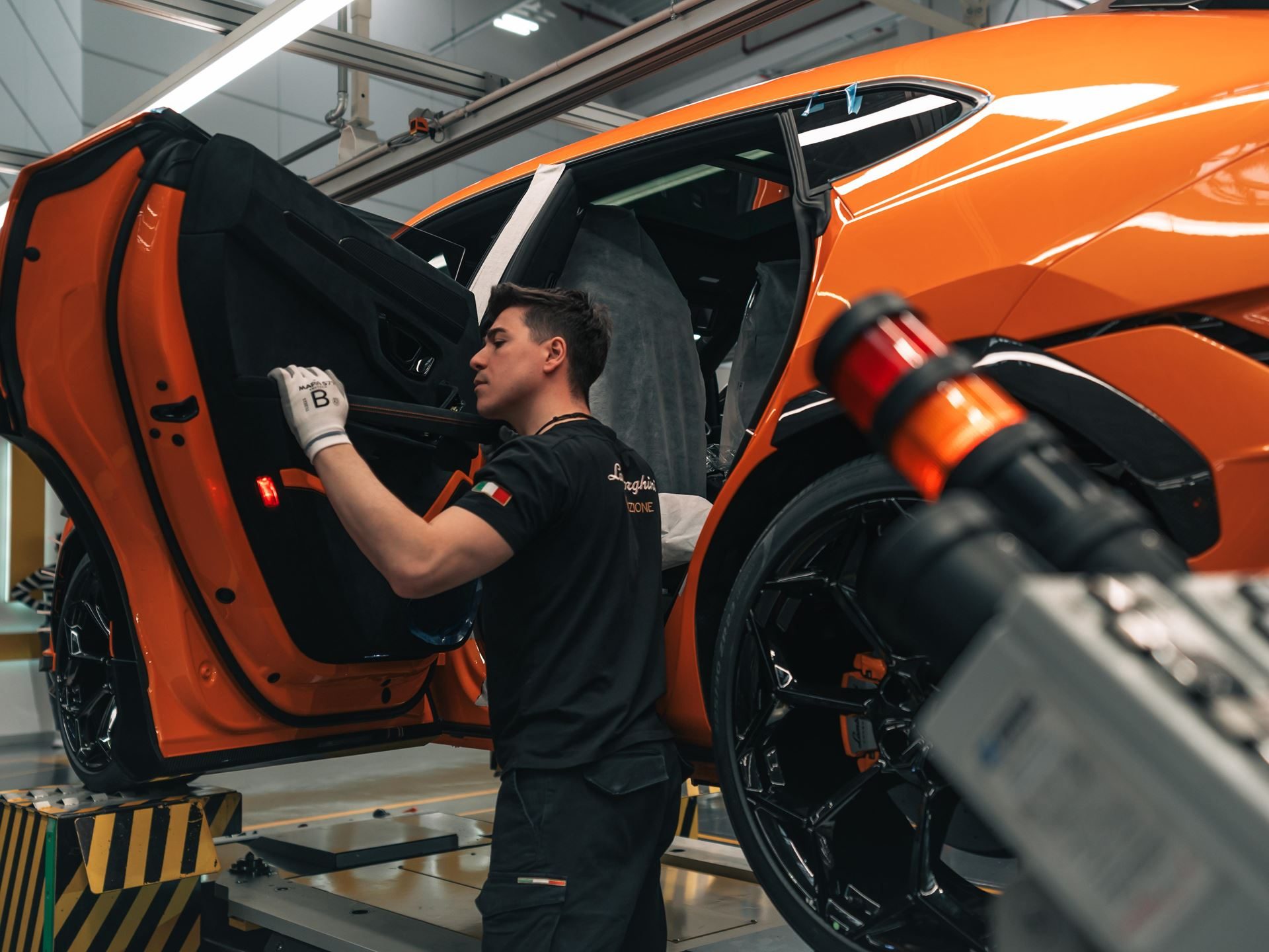 Lamborghini'S Hybrid Bet Pays Off: Record Deliveries, A Killed Ev, And 26.6% Margins Tell The Real Story 7 Lamborghini worker installing an interior panel on an orange urus on the production line