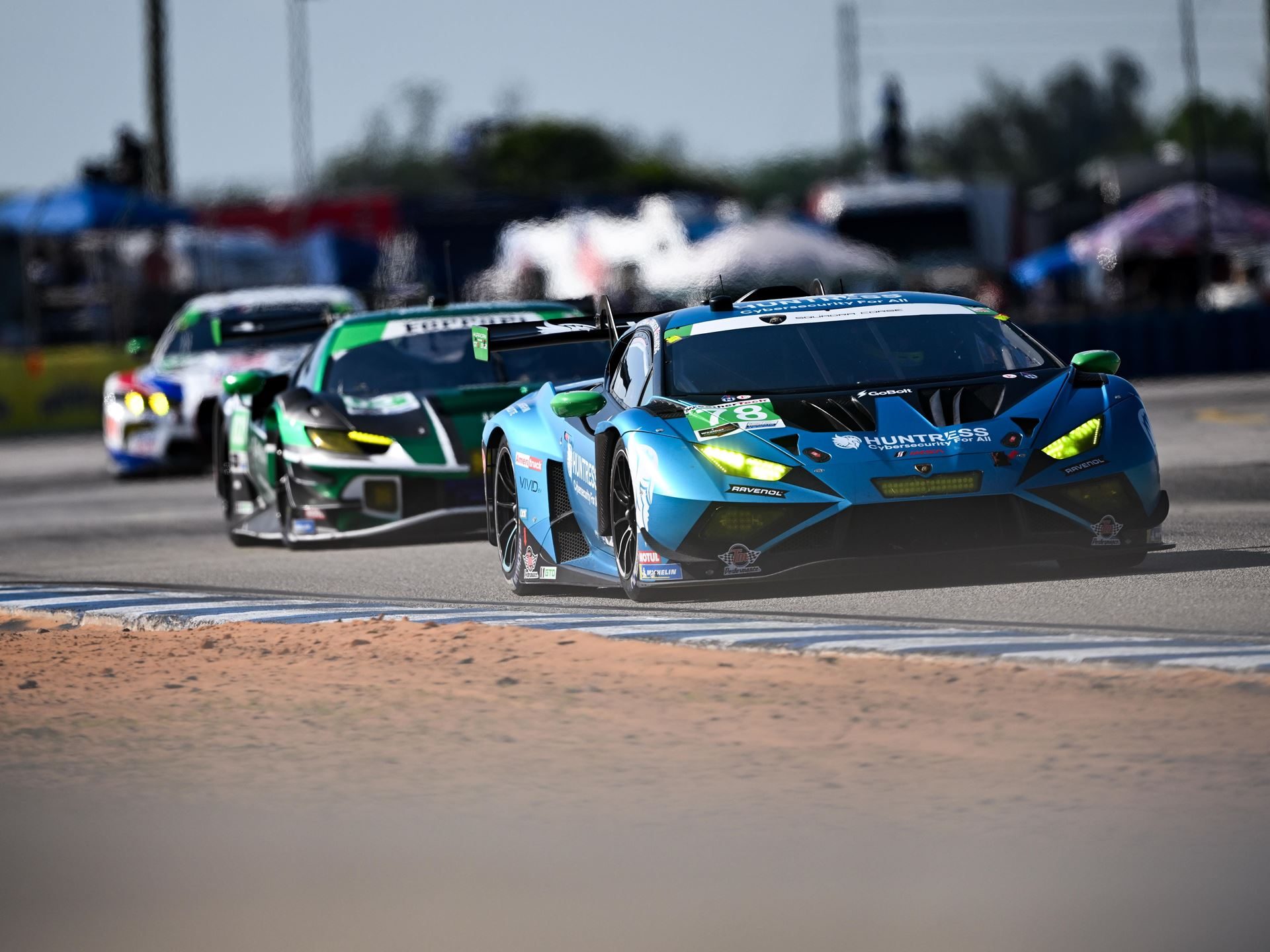 The #78 forte racing lamborghini huracán gt3 evo2 in blue and green livery leading two cars on track at sebring