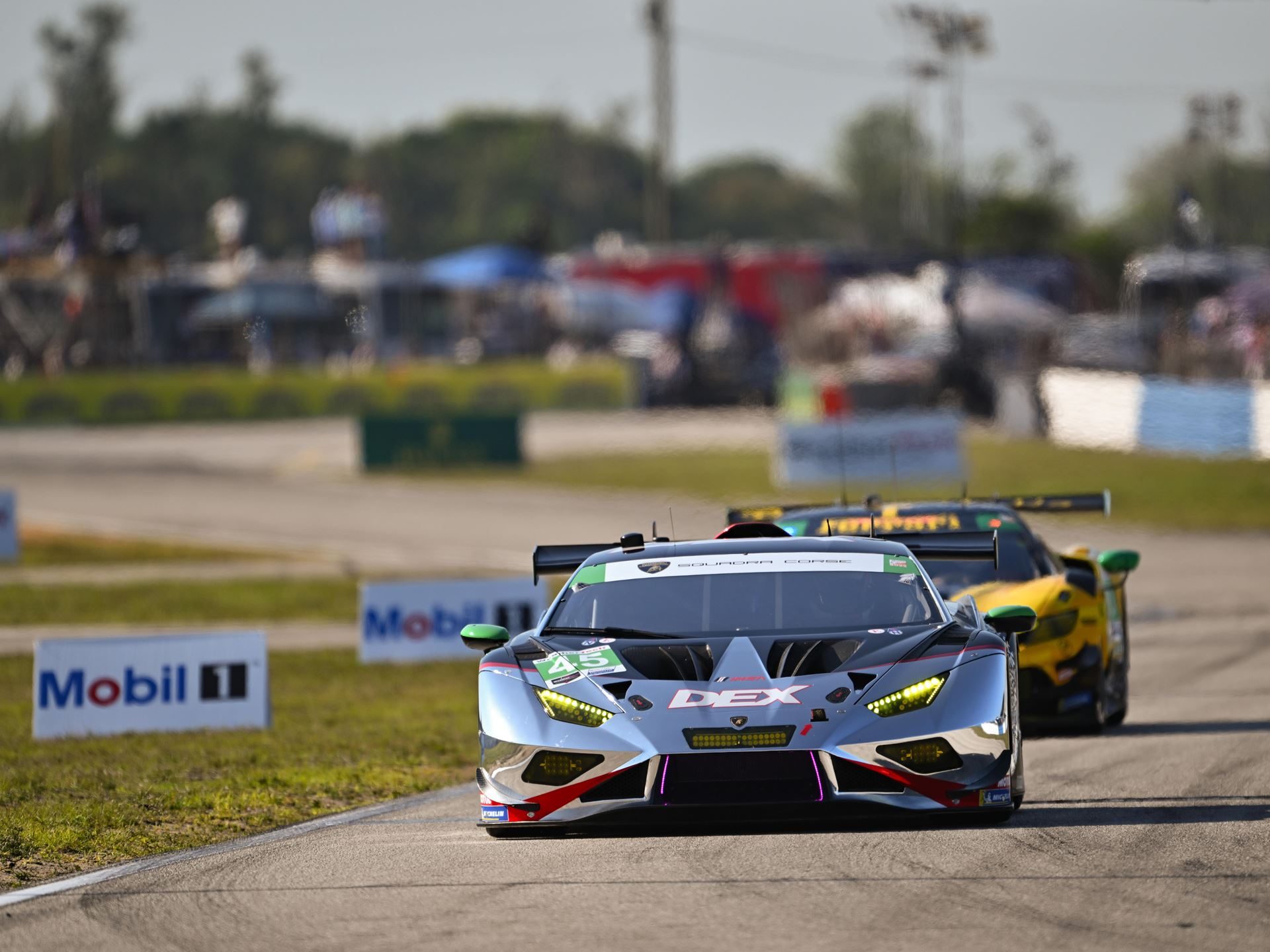The #45 wtr lamborghini huracán gt3 evo2 in silver and red livery approaching head-on at sebring with spectators in the background