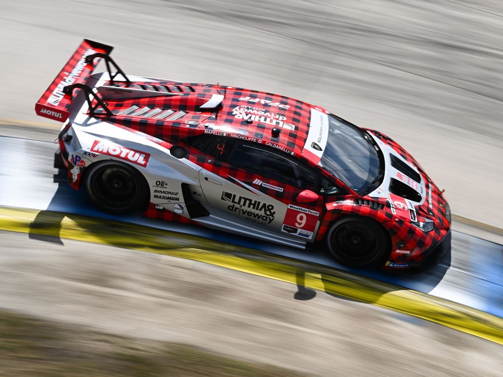 The #9 Pfaff Motorsports Lamborghini Huracán GT3 EVO2 in red and white plaid livery cornering at speed during the 2025 12 Hours of Sebring