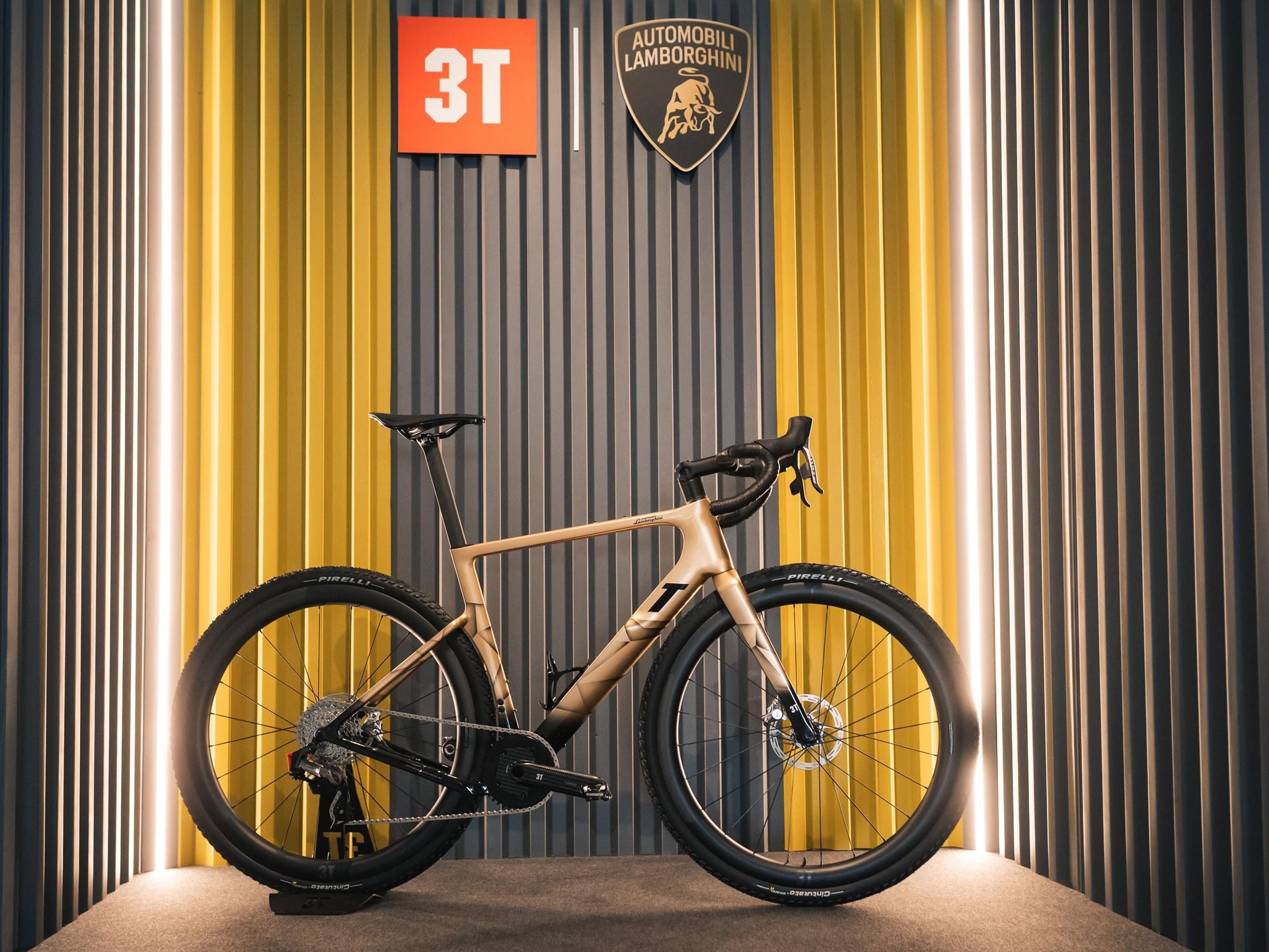 Lamborghini'S Porto Cervo Lounge Returns For A Seventh Summer, Now Showcasing An All-Hybrid Lineup 7 Gold-colored 3t racemax x automobili lamborghini gravel bicycle displayed against a branded wall at the porto cervo lounge
