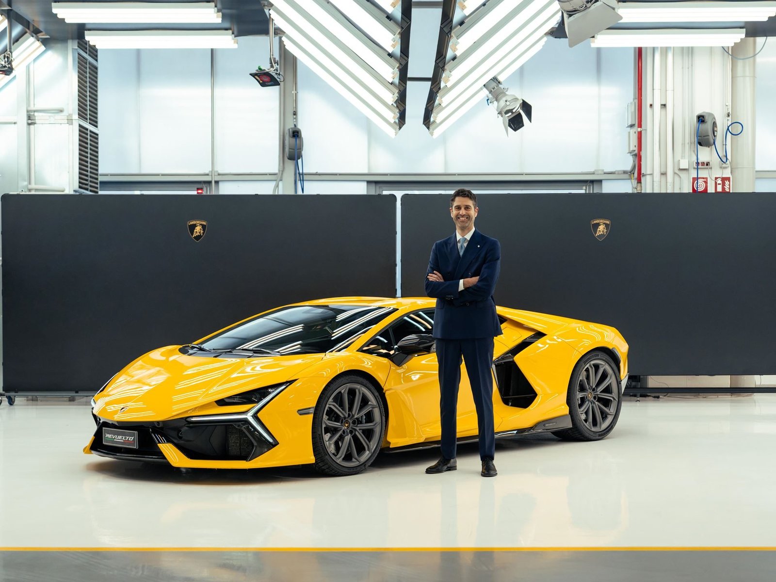 Matteo Ortenzi standing next to a yellow Lamborghini Revuelto in a studio setting