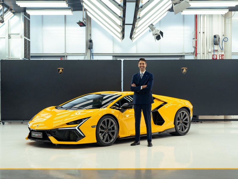 Matteo Ortenzi standing next to a yellow Lamborghini Revuelto in a studio setting