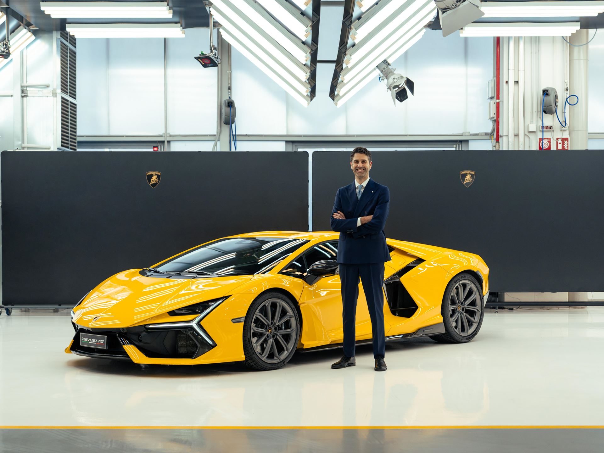Matteo ortenzi standing next to a yellow lamborghini revuelto in a studio setting