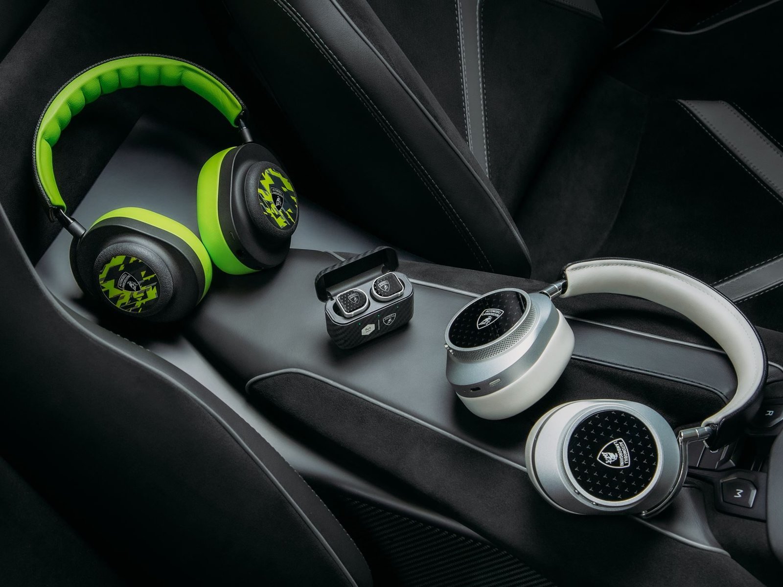 Three sets of Master & Dynamic x Automobili Lamborghini headphones and earbuds displayed on a Lamborghini car seat interior, showing yellow Alcantara earcups and hexagonal design details